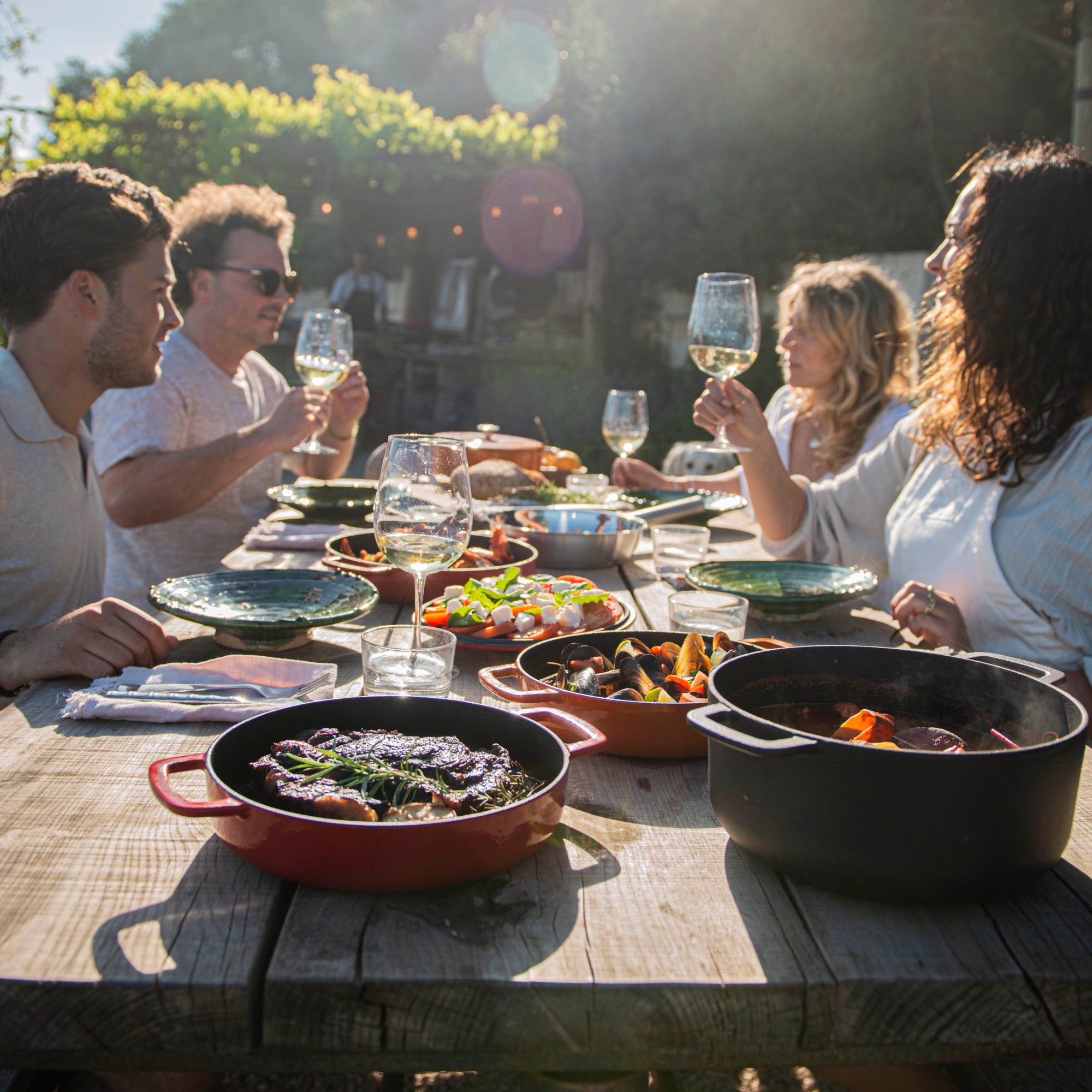 Combekk | Cast Iron Cook ware displayed at a sunlit outdoor dinner with friends enjoying a meal.