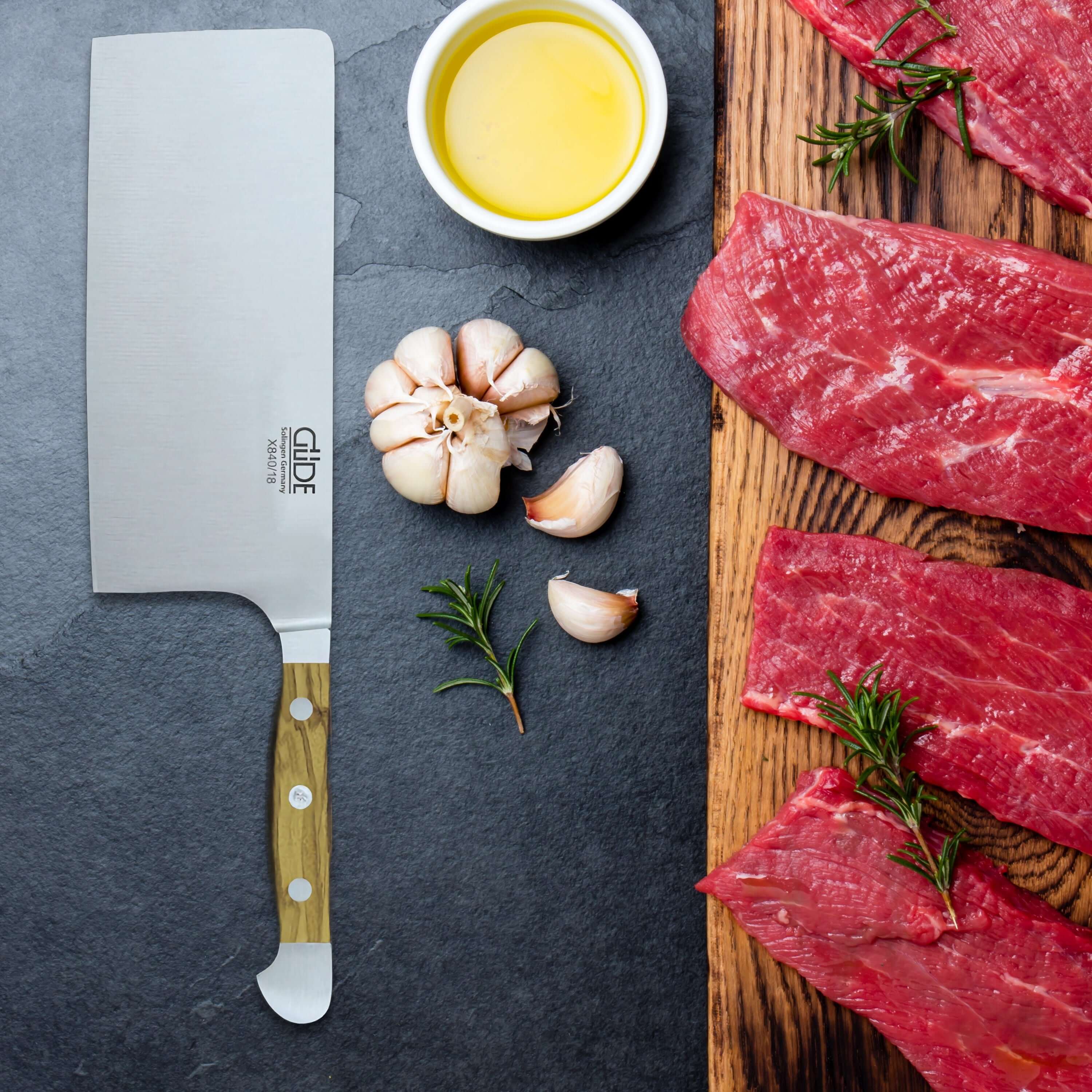 Japanese Cleaver Knife with garlic and raw meat on a wooden cutting board