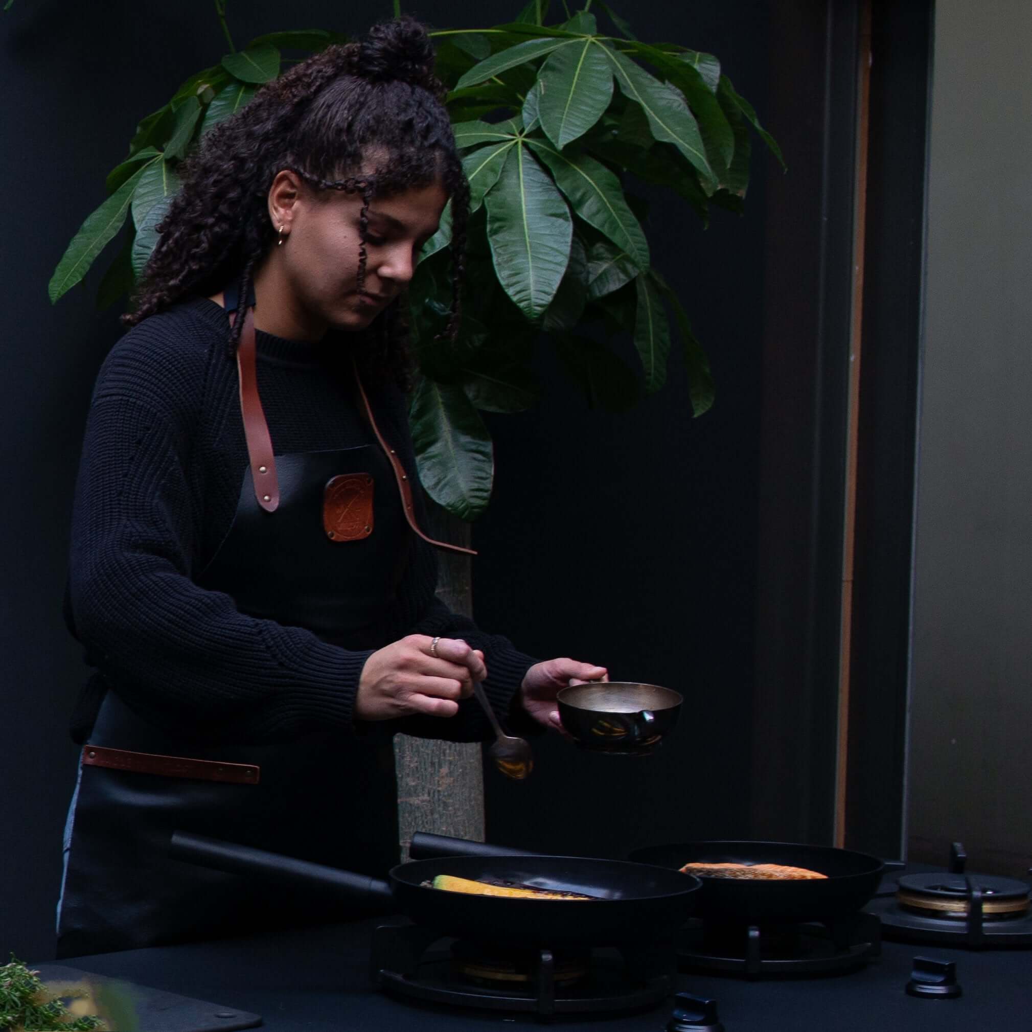 Woman cooking with COMBEKK | Fry Pans in a modern kitchen setting, showcasing ceramic aluminium design.