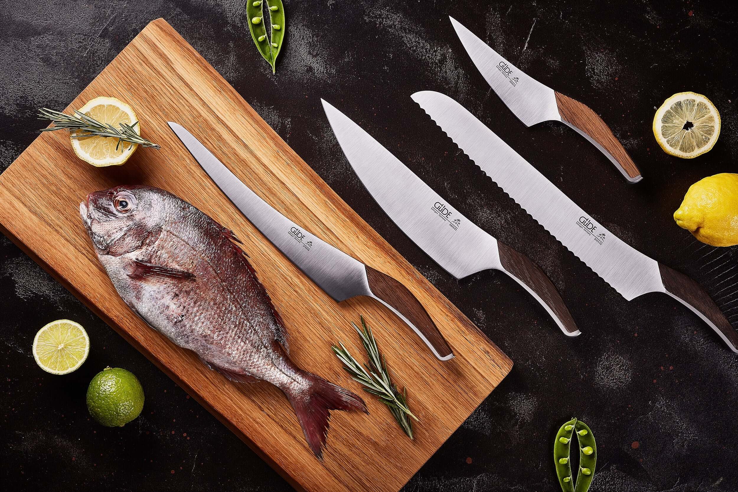 GÜDE Knives - Solingen Germany displayed with fresh fish on a wooden cutting board, showcasing their craftsmanship and design.