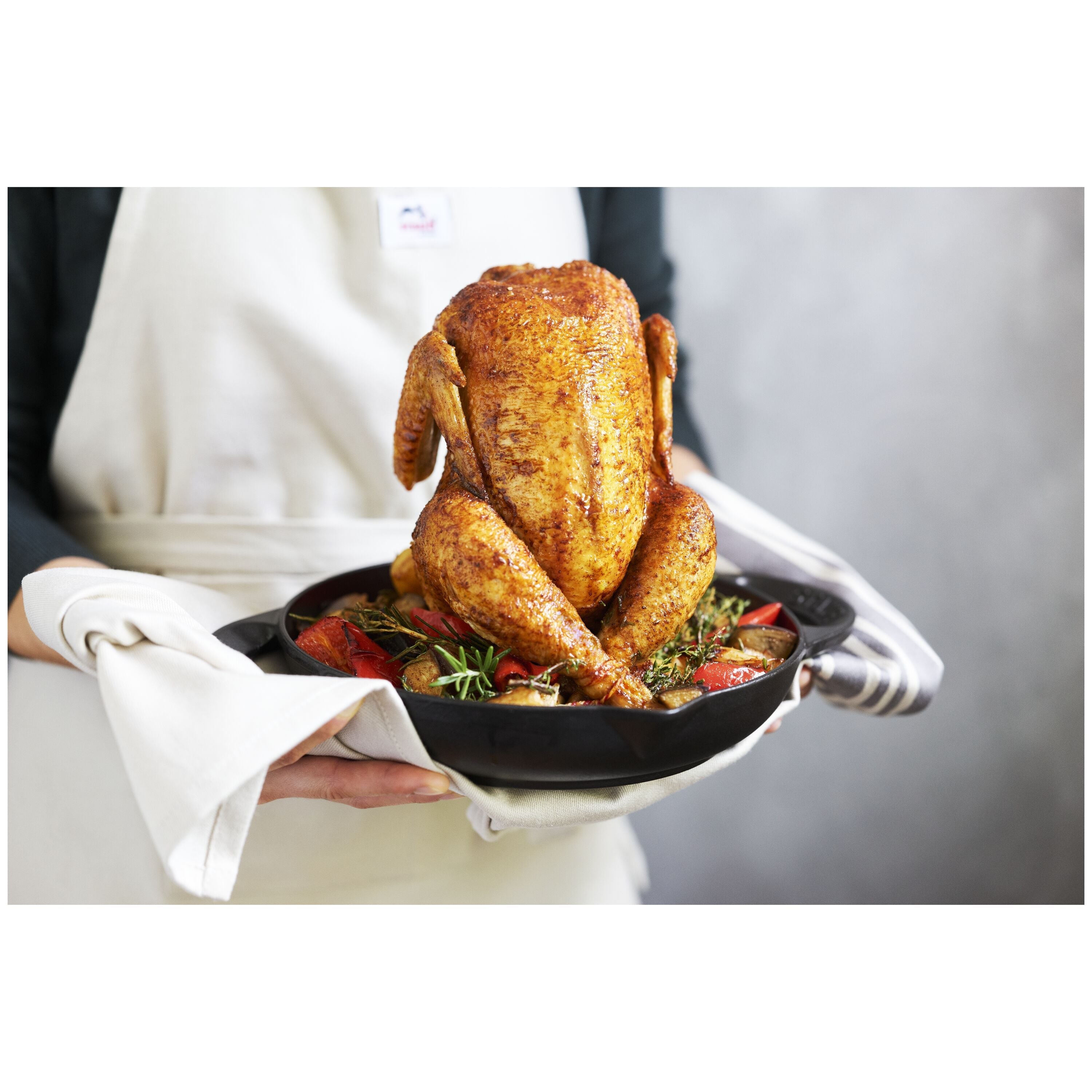 Cooked chicken in STAUB Specialities Cast Iron Round Roaster with herbs and vegetables.