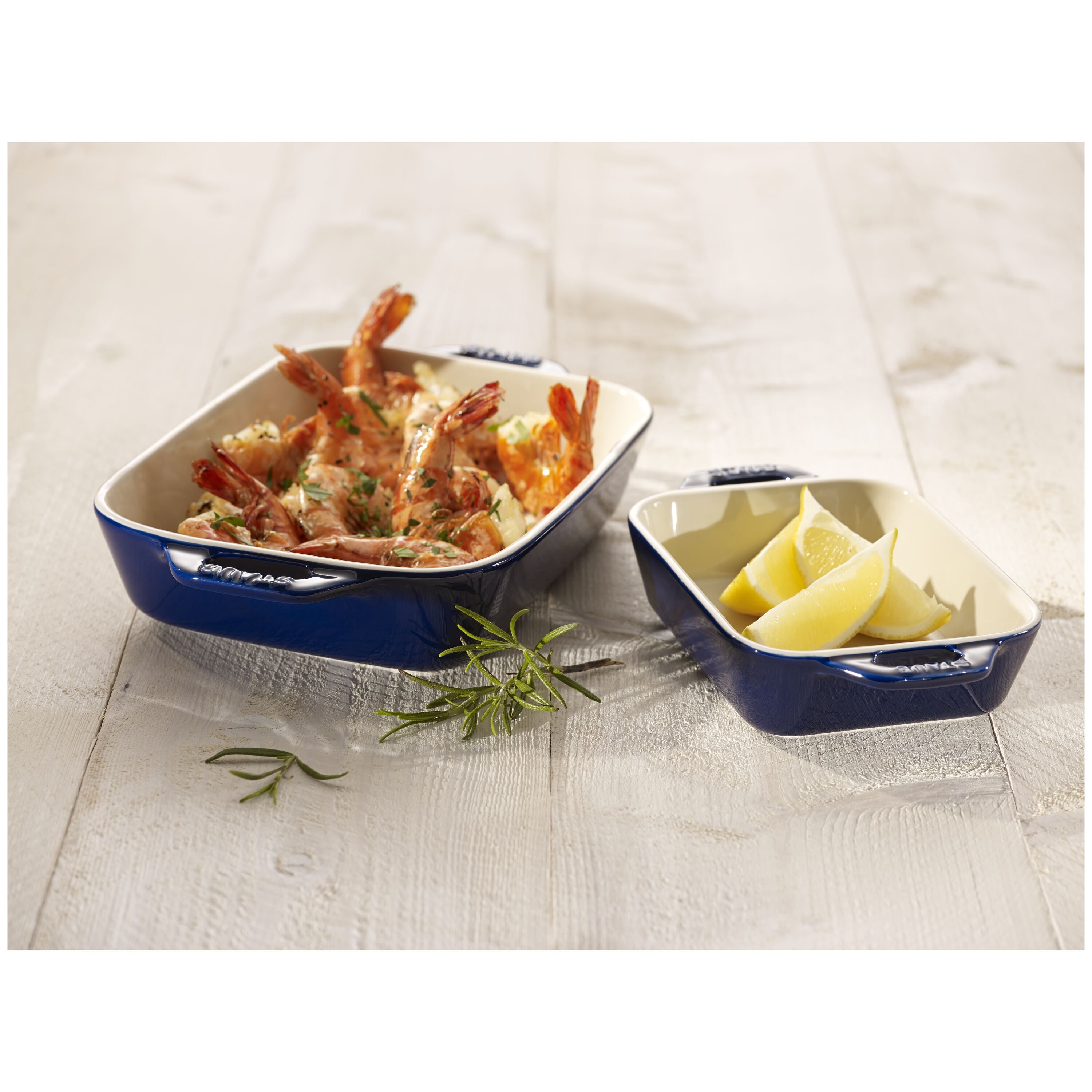 Blue STAUB Ceramique Ceramic Rectangular Oven Dish with fried shrimp and lemon wedges on a light wooden surface.