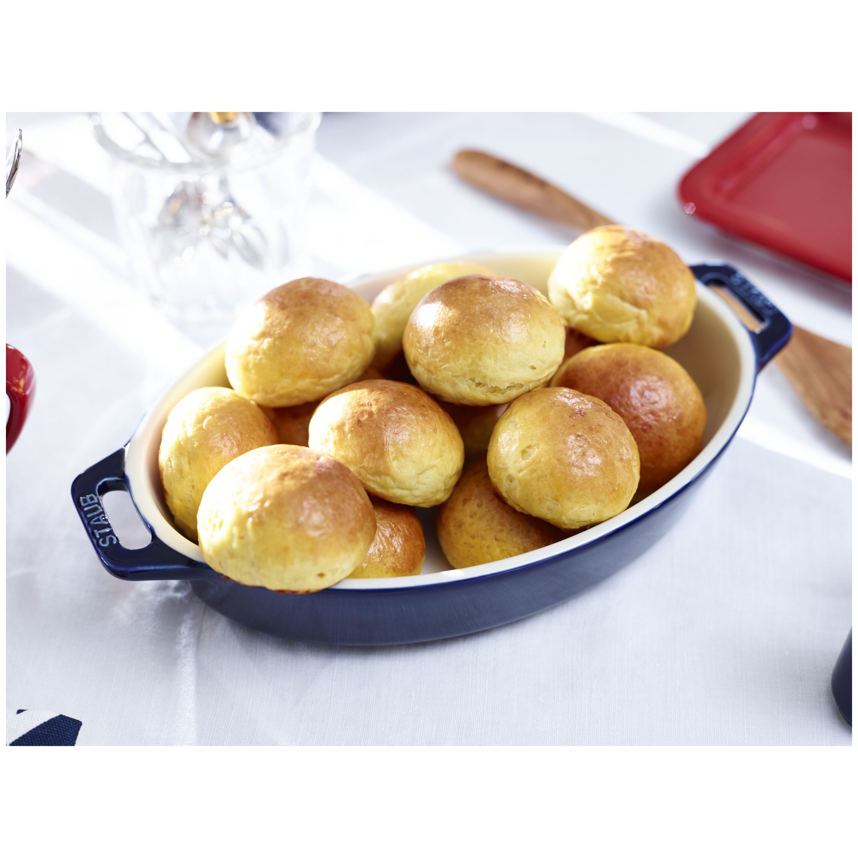 Bowl of bread rolls on a white surface with a red container in the background