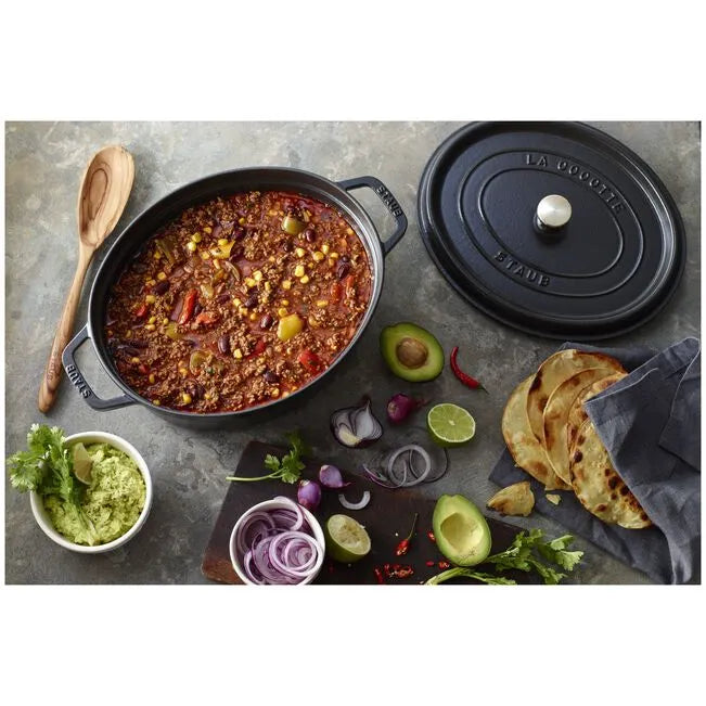 Staub cookware with chili, guacamole, and tortillas on a gray surface