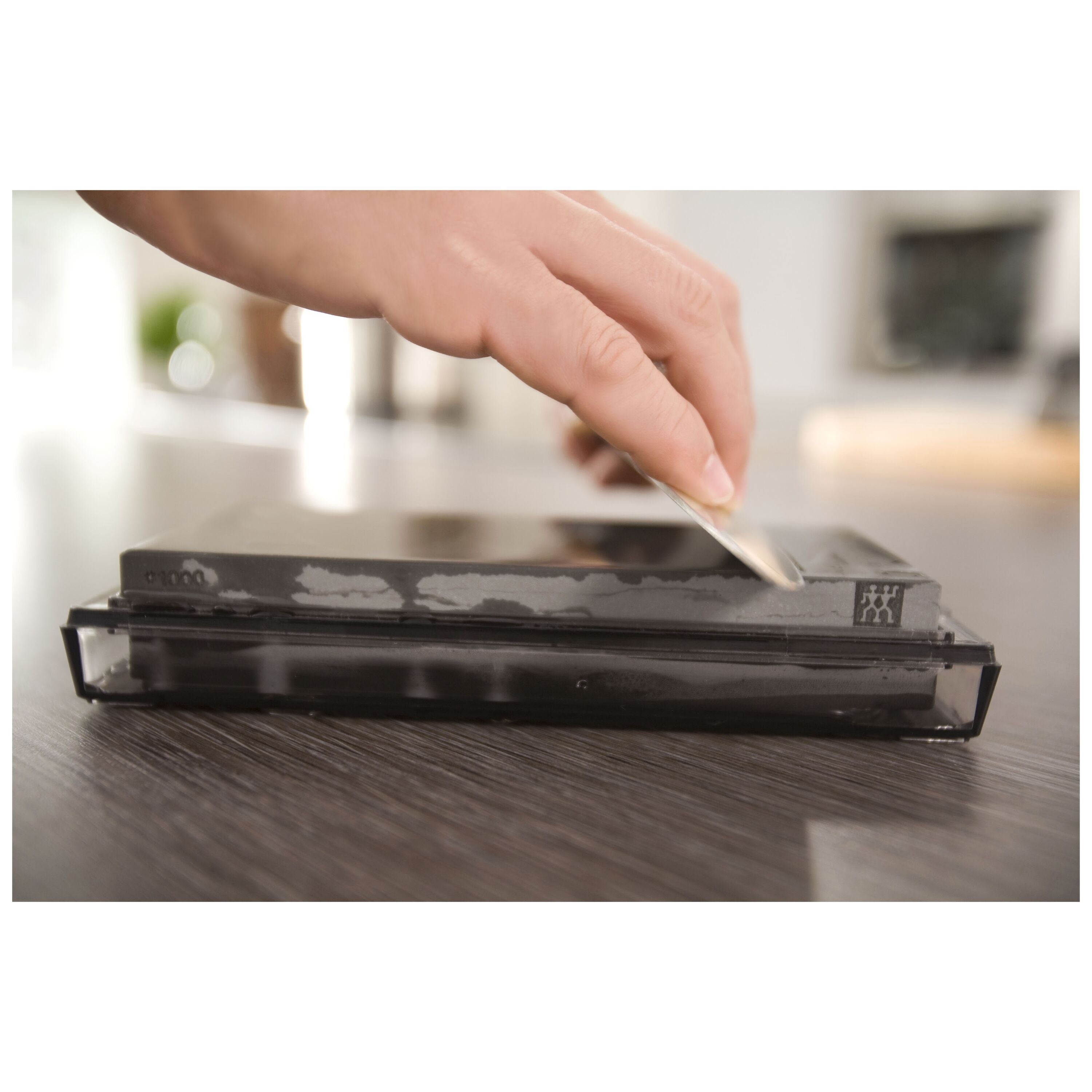 Person using a knife sharpener on a kitchen counter