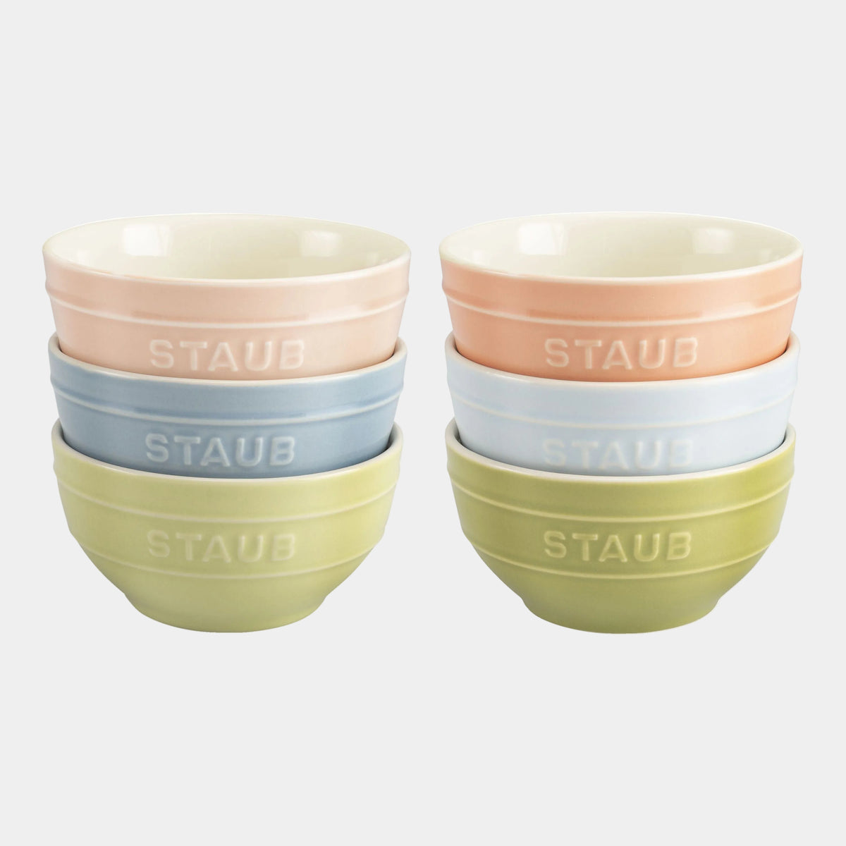 Set of four colorful Staub bowls stacked on a white background