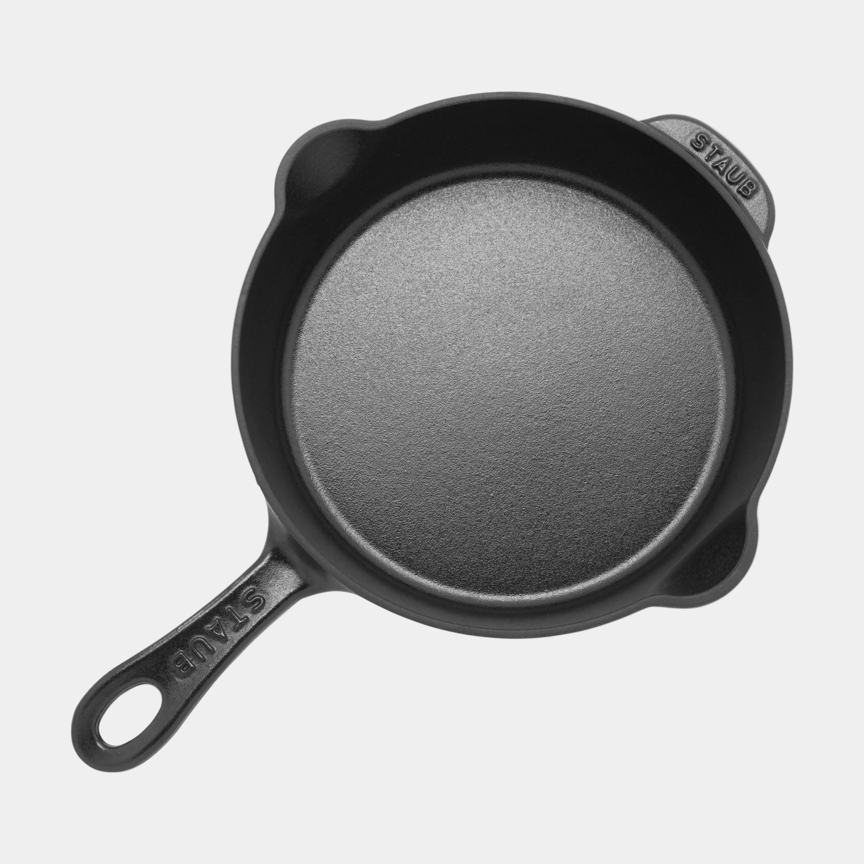 Black cast iron skillet with 'Staub' branding on a white background