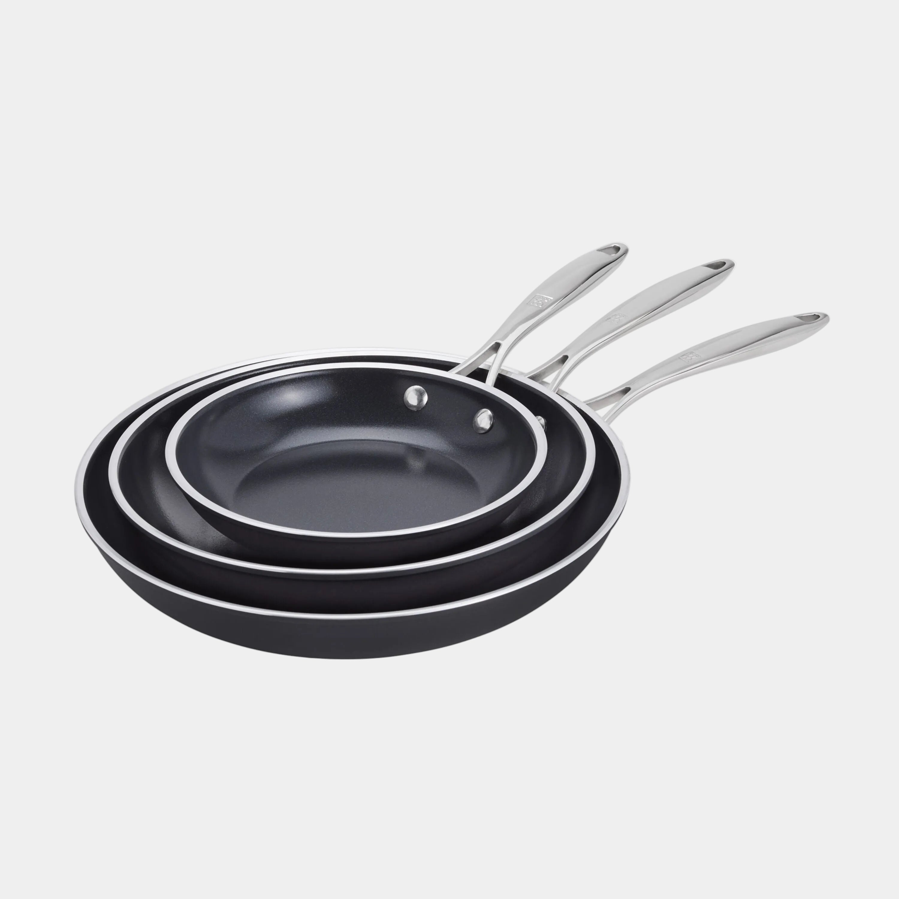 Set of three black frying pans with silver handles on a white background