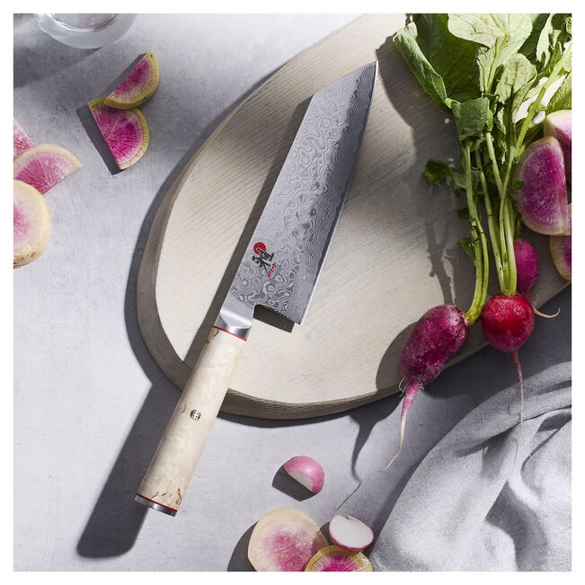 Chef's knife with a wooden handle on a cutting board with radishes