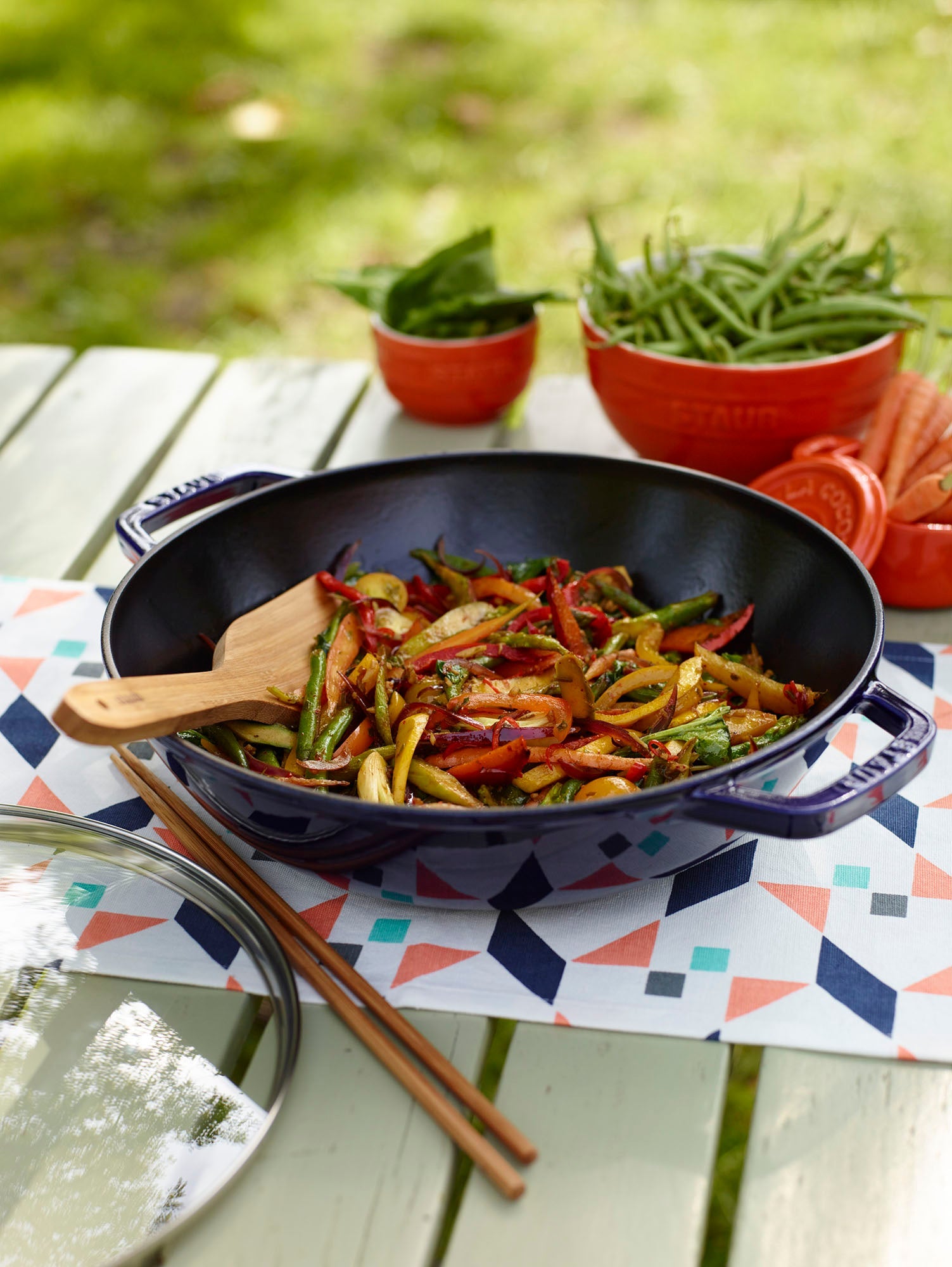 Wok with stir-fried vegetables on a table outdoors