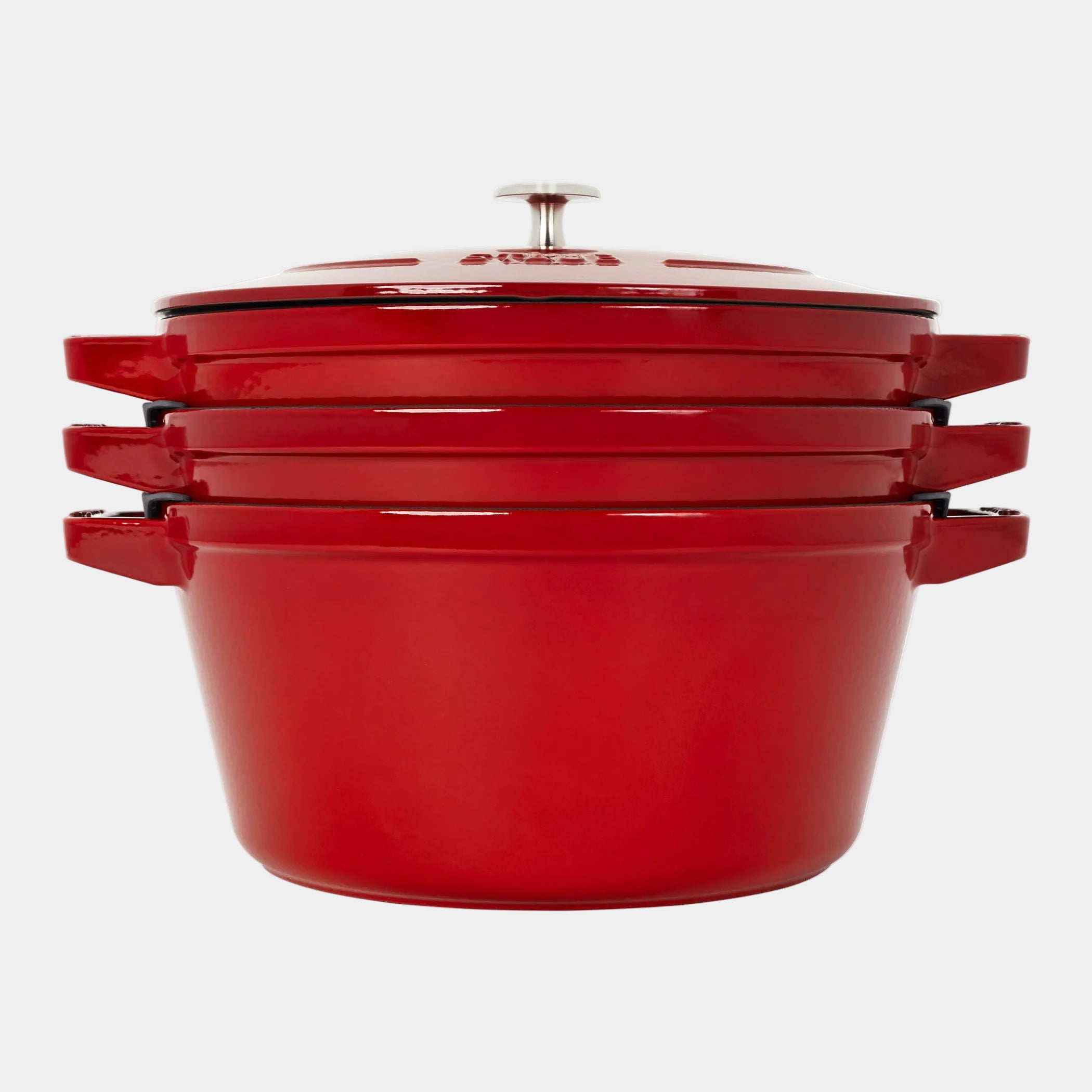 Set of red enameled cast iron cookware on a white background