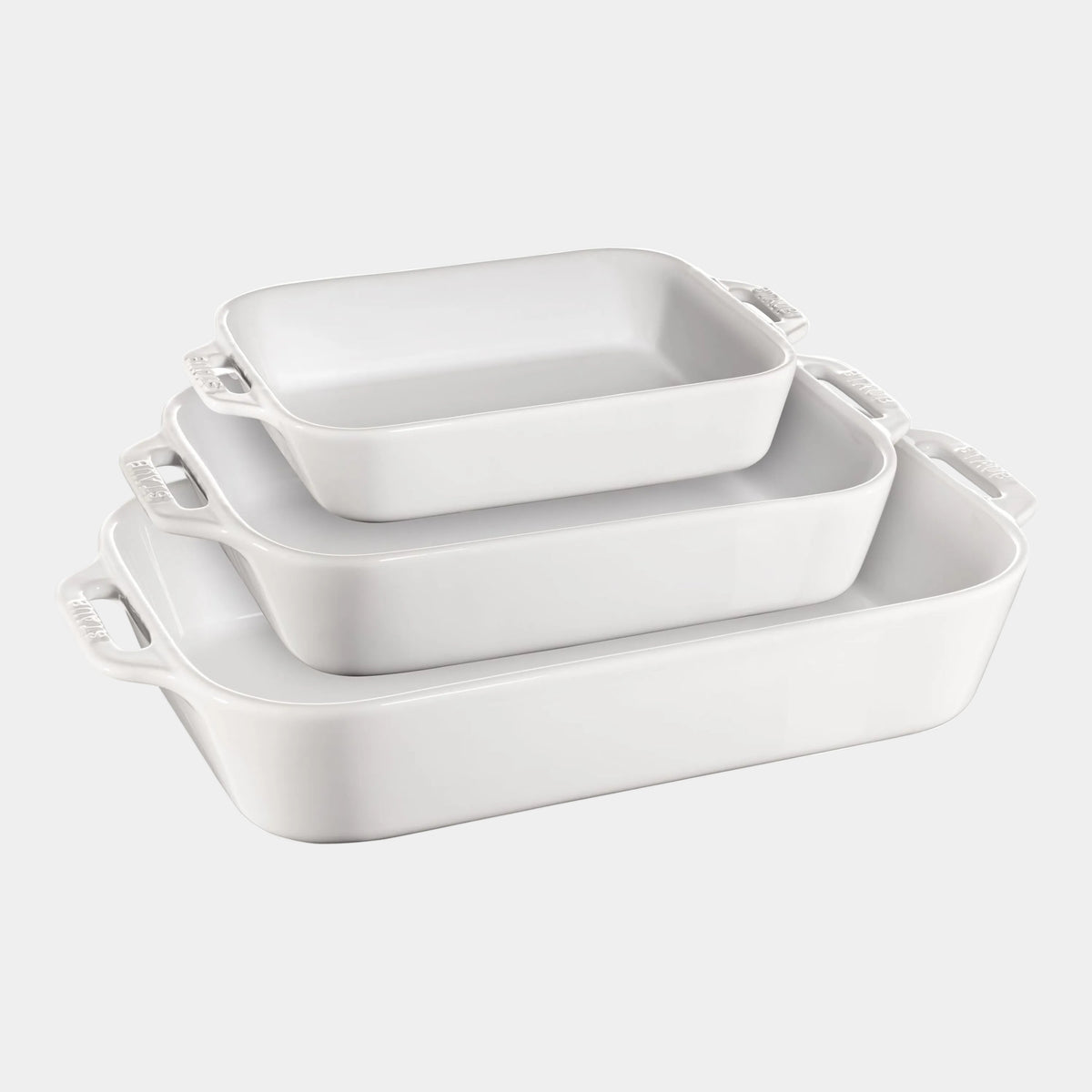 Set of three white ceramic baking dishes of different sizes on a white background