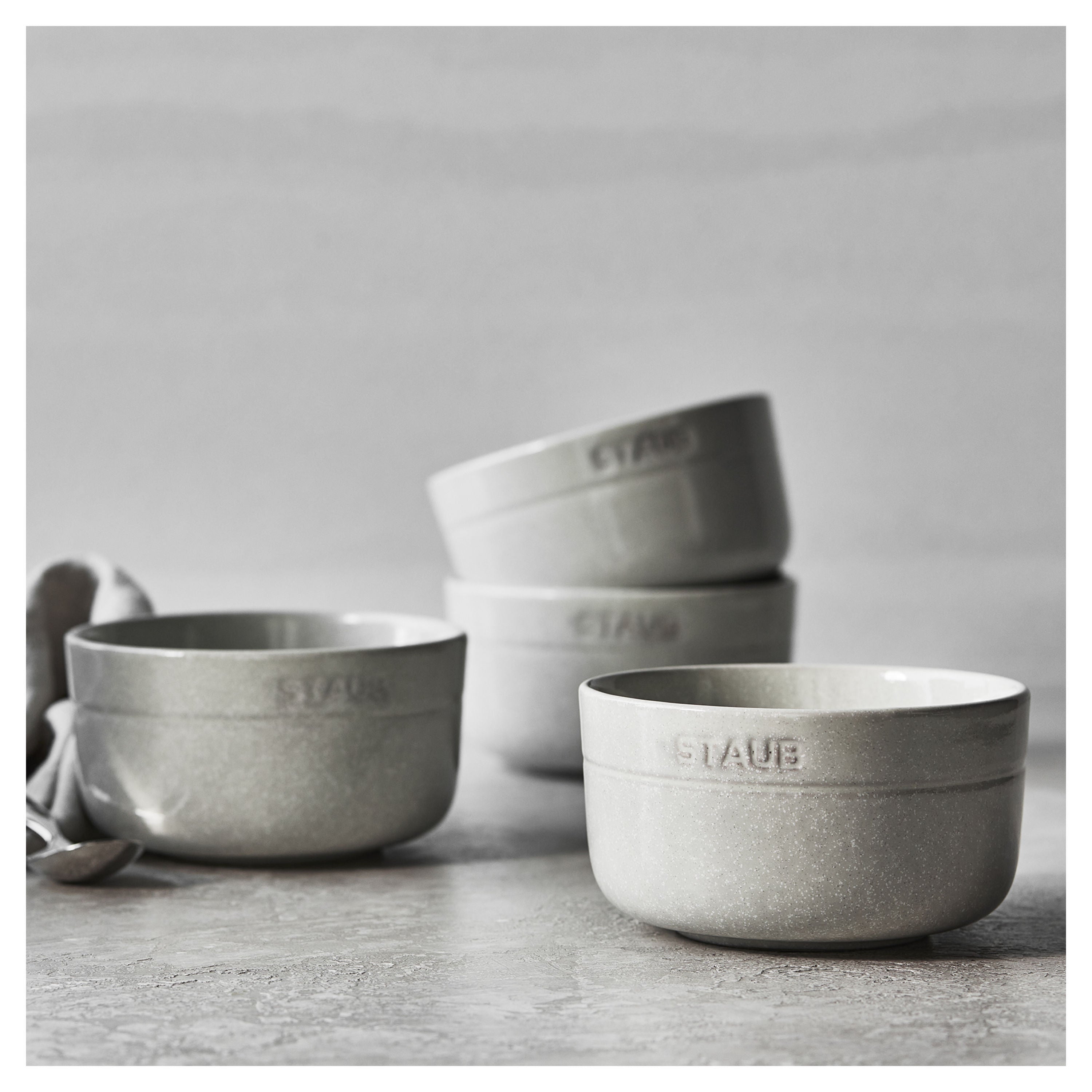 Set of gray ceramic bowls with 'Stauba' branding on a light gray background