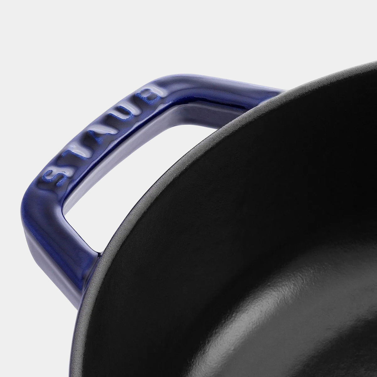 Close-up of a Staub cookware handle with brand name on a white background