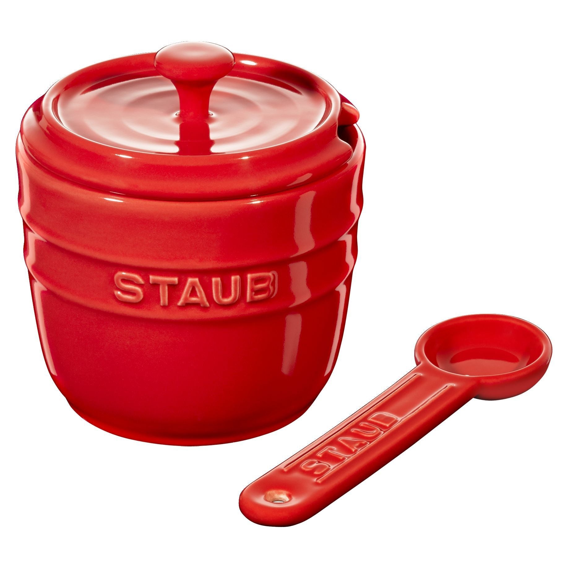 Red Staub ceramic container with lid and measuring spoon on a white background