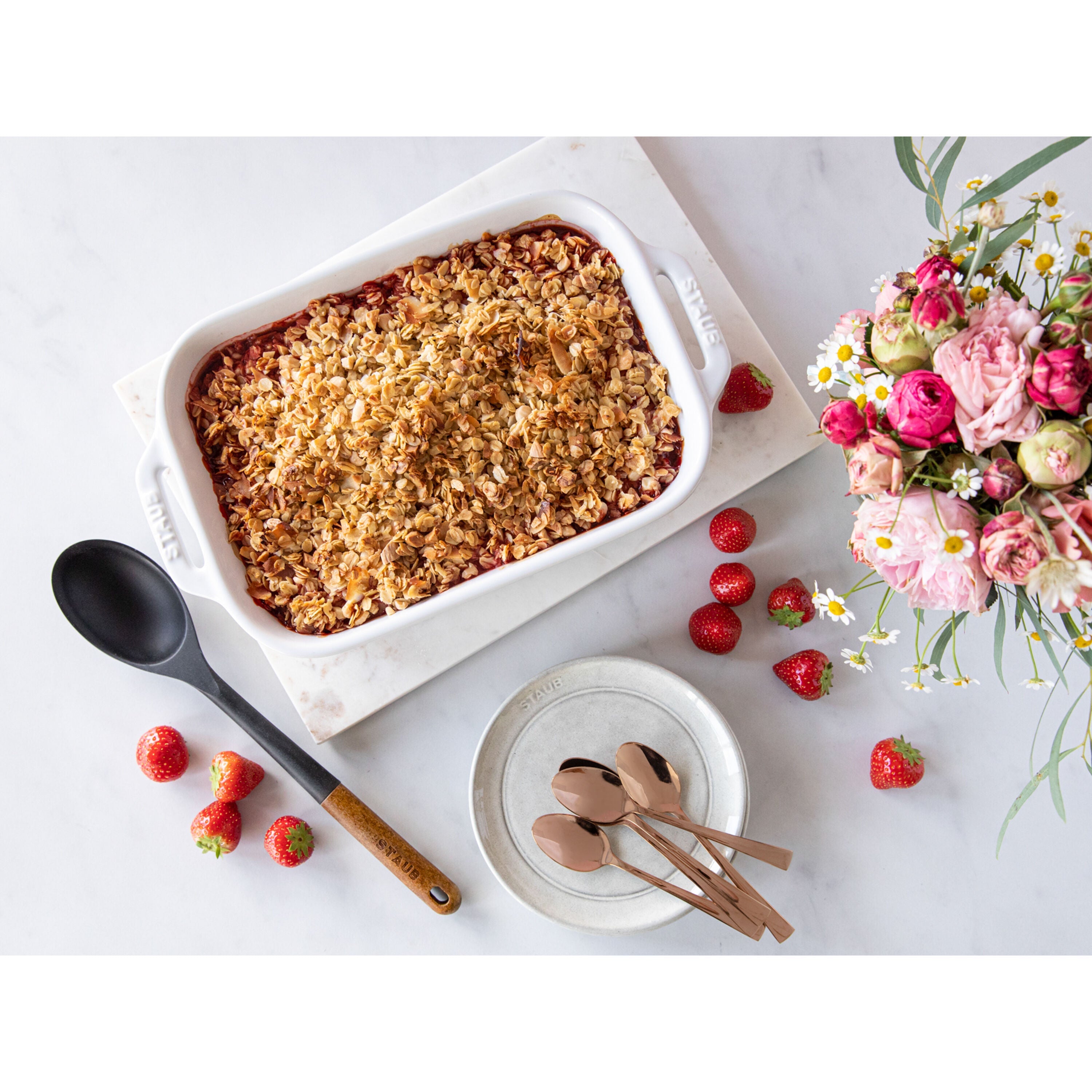 STAUB Ceramique 4.4 L Ceramic Rectangular Oven Dish in use with a baked dessert, surrounded by strawberries and flowers.