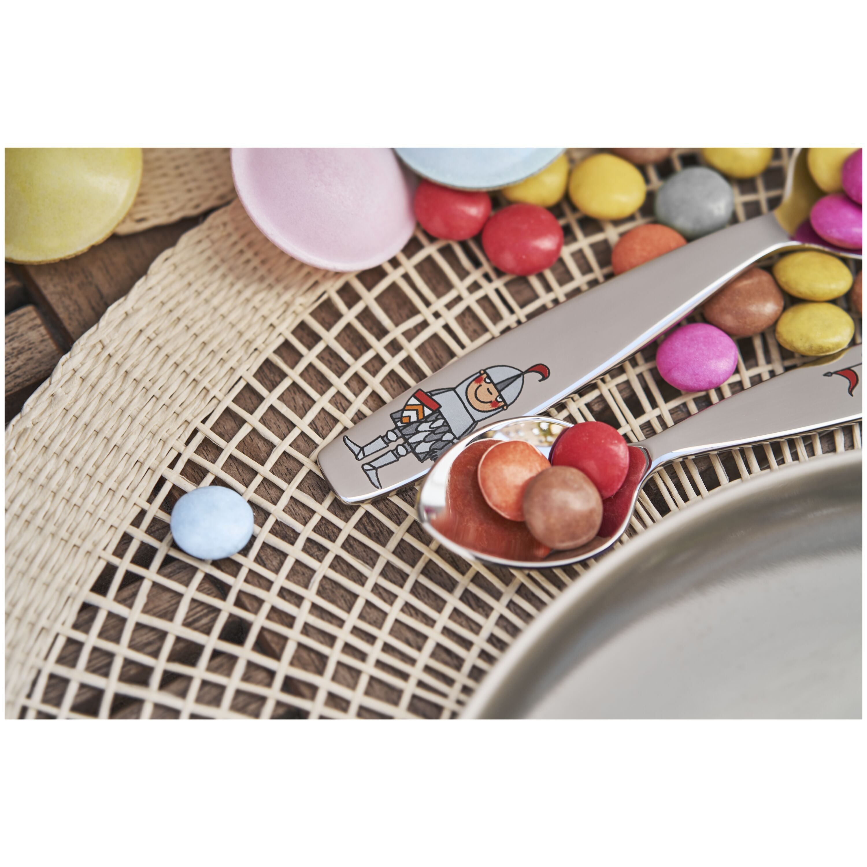Spoon with colorful candies on a woven mat