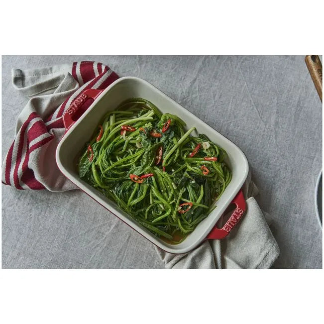 STAUB Ceramique Ceramic Rectangular Oven Dish with salad and red peppers on a gray surface with a red and white towel.