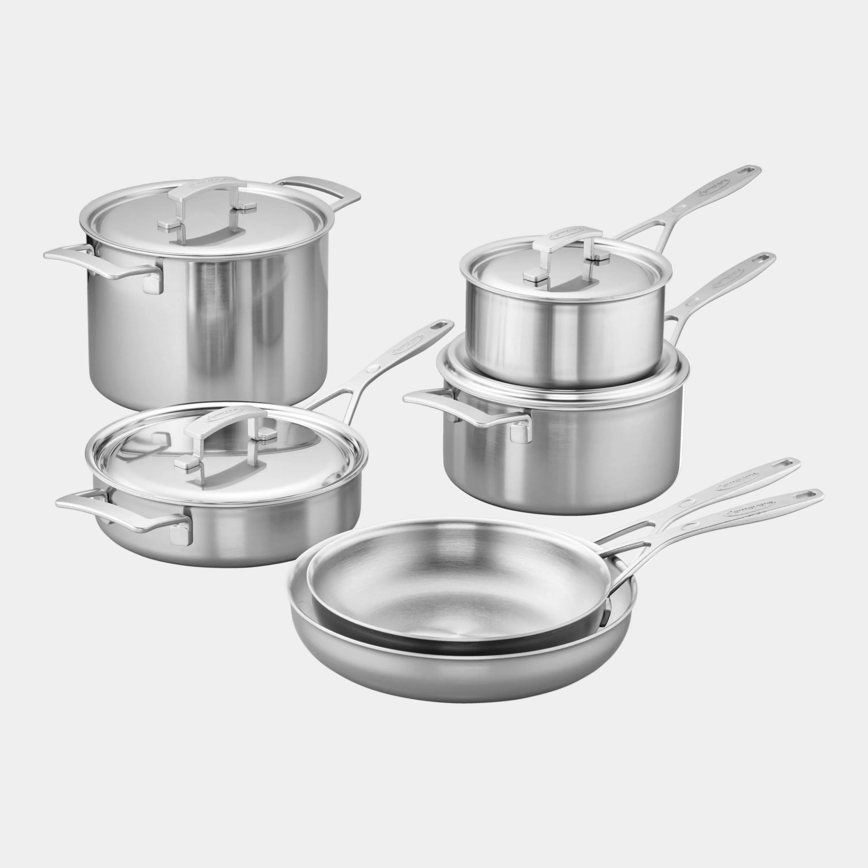 Set of stainless steel cookware including pots, pans, and lids on a white background