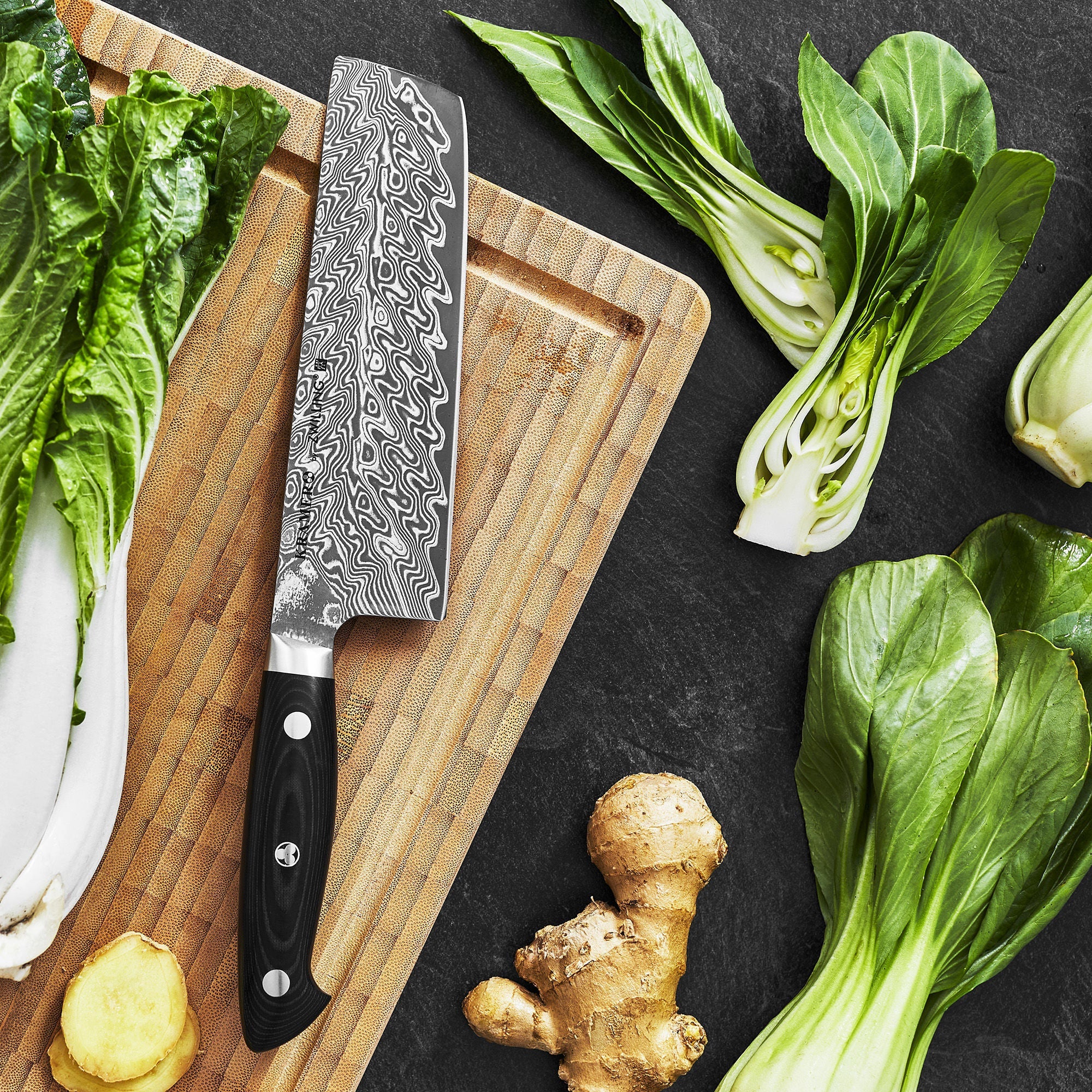 Cleaver knife on a wooden cutting board with vegetables on a dark surface