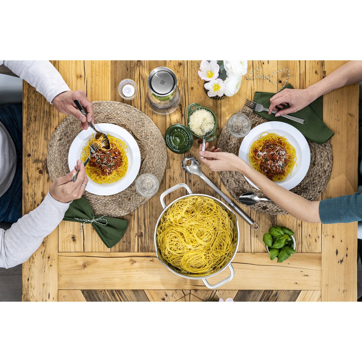 Two people enjoying a meal of pasta at a wooden table.