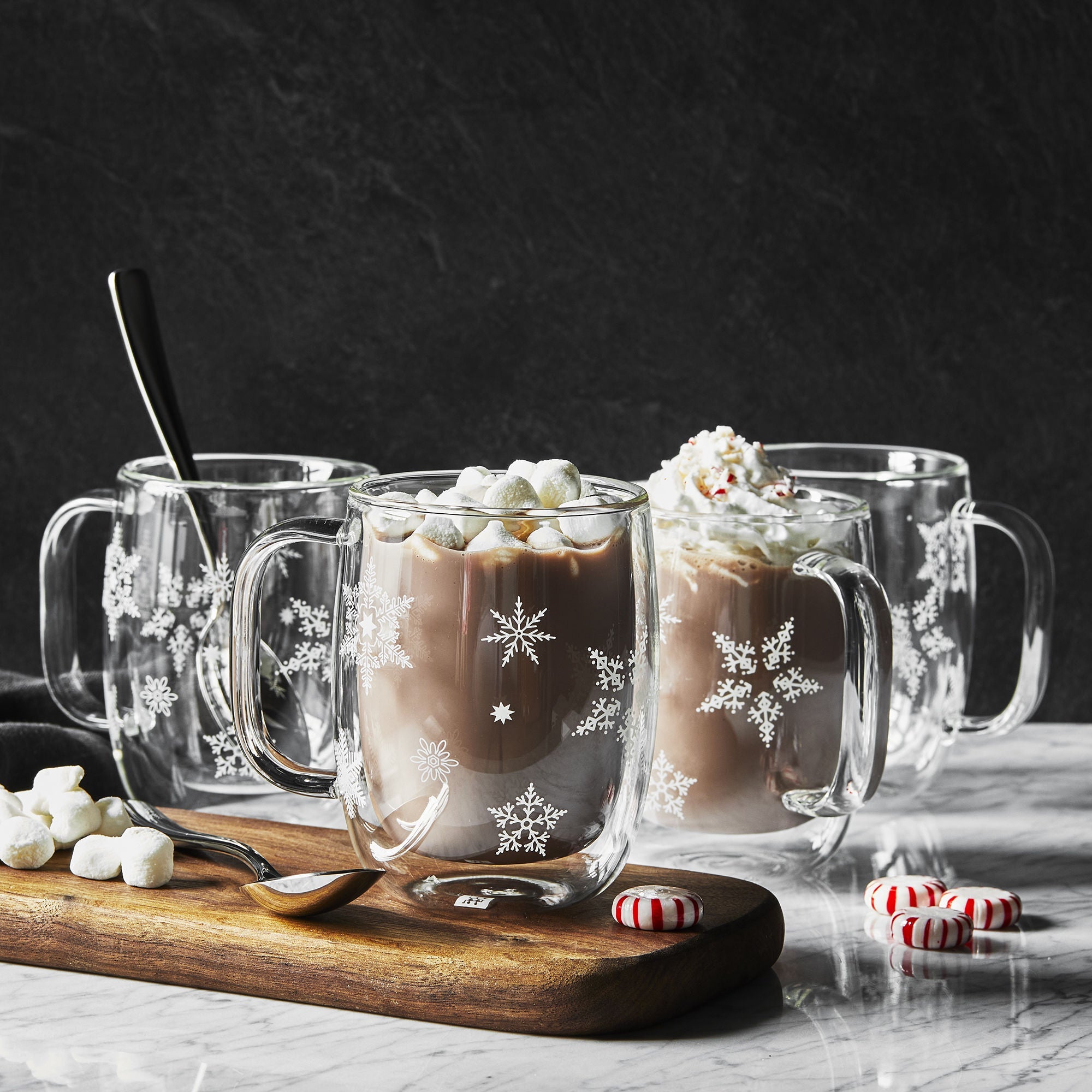 Clear glass ZWILLING Sorrento Plus Snowflake Double-Walled Mug designs filled with hot chocolate and marshmallows on a dark background.