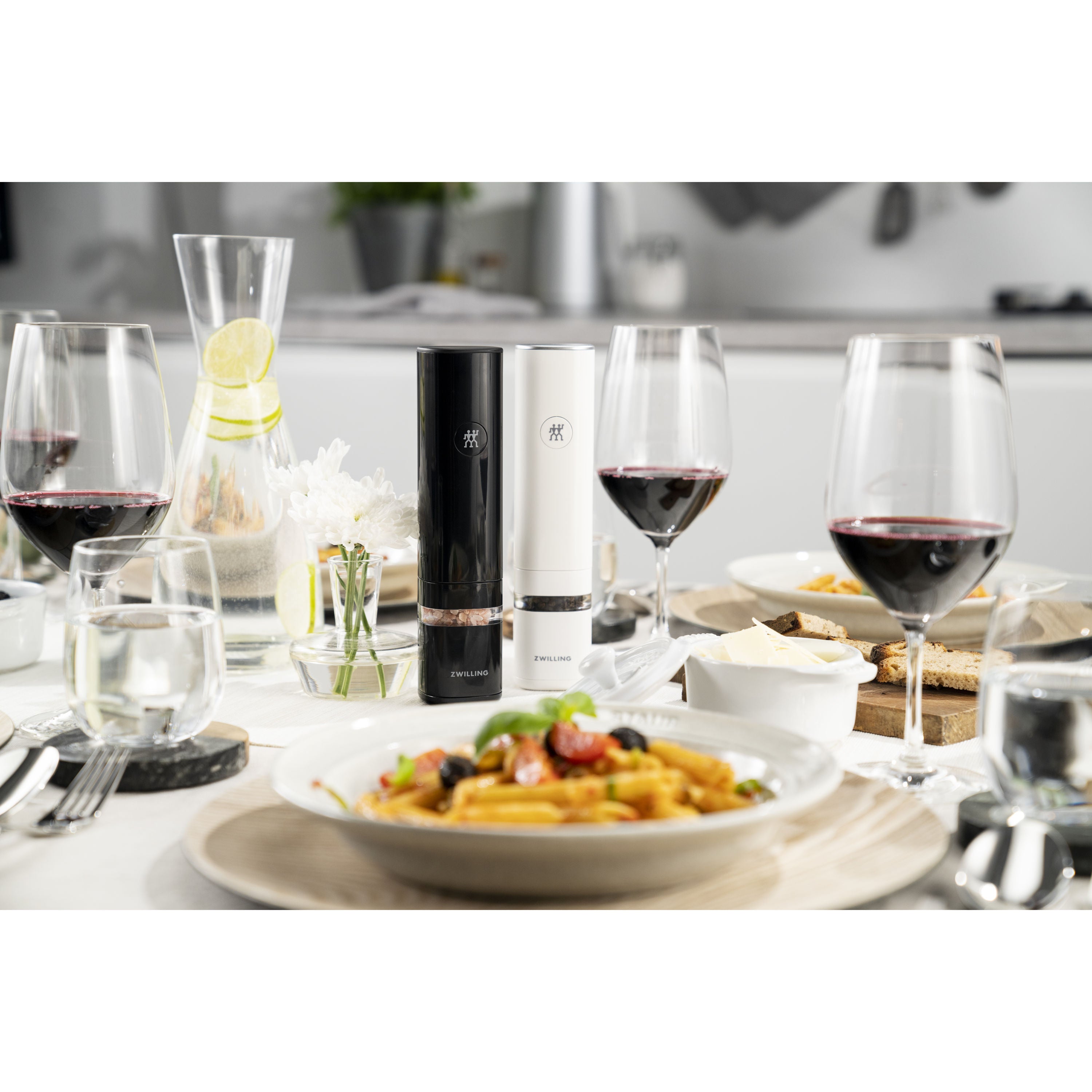 Dining table with pasta dish, wine glasses, and a bottle of wine.