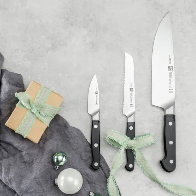 Set of knives with black handles on a gray surface with decorative elements.