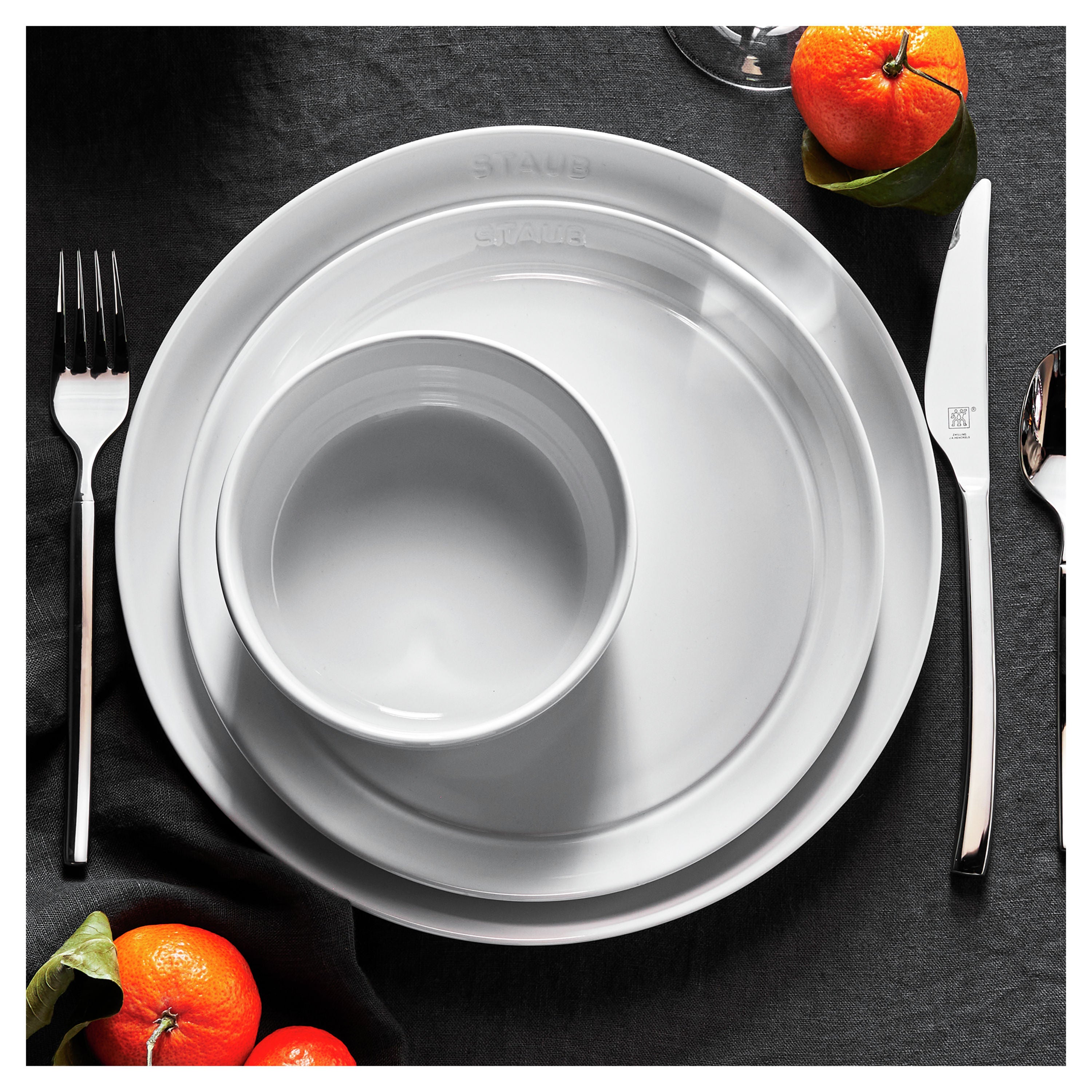 White ceramic plates with silverware on a dark surface