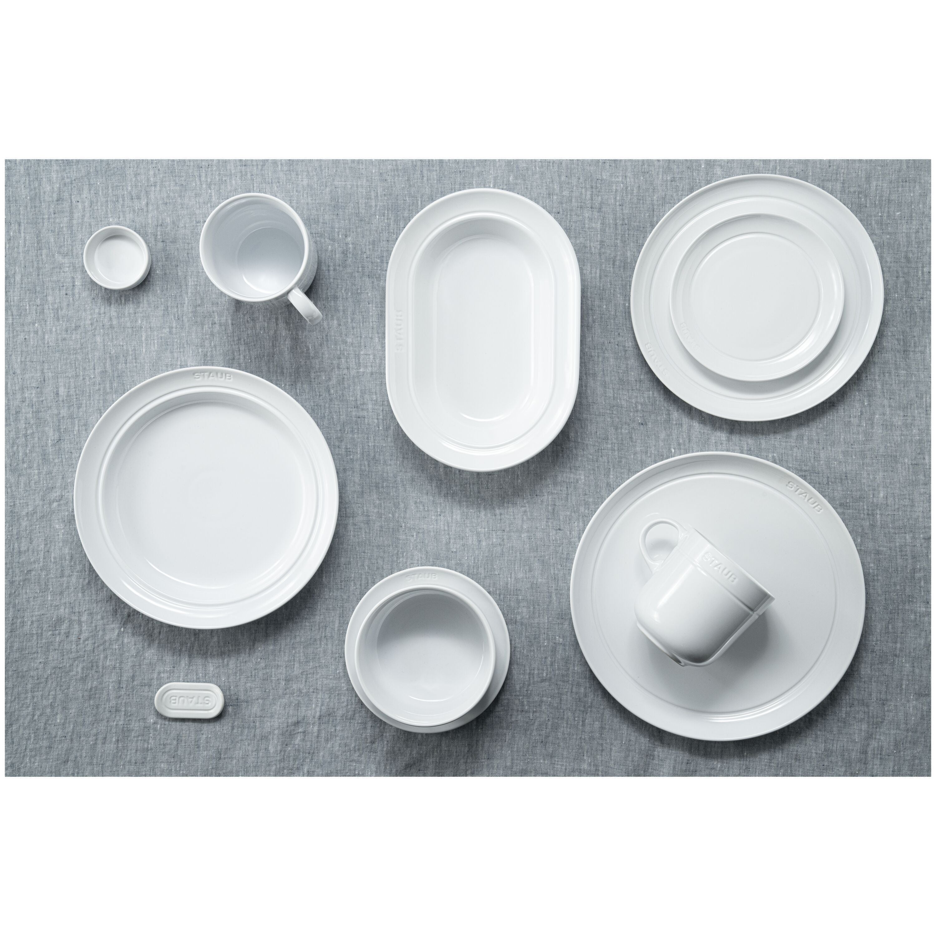 Set of white ceramic dishes on a gray textured surface