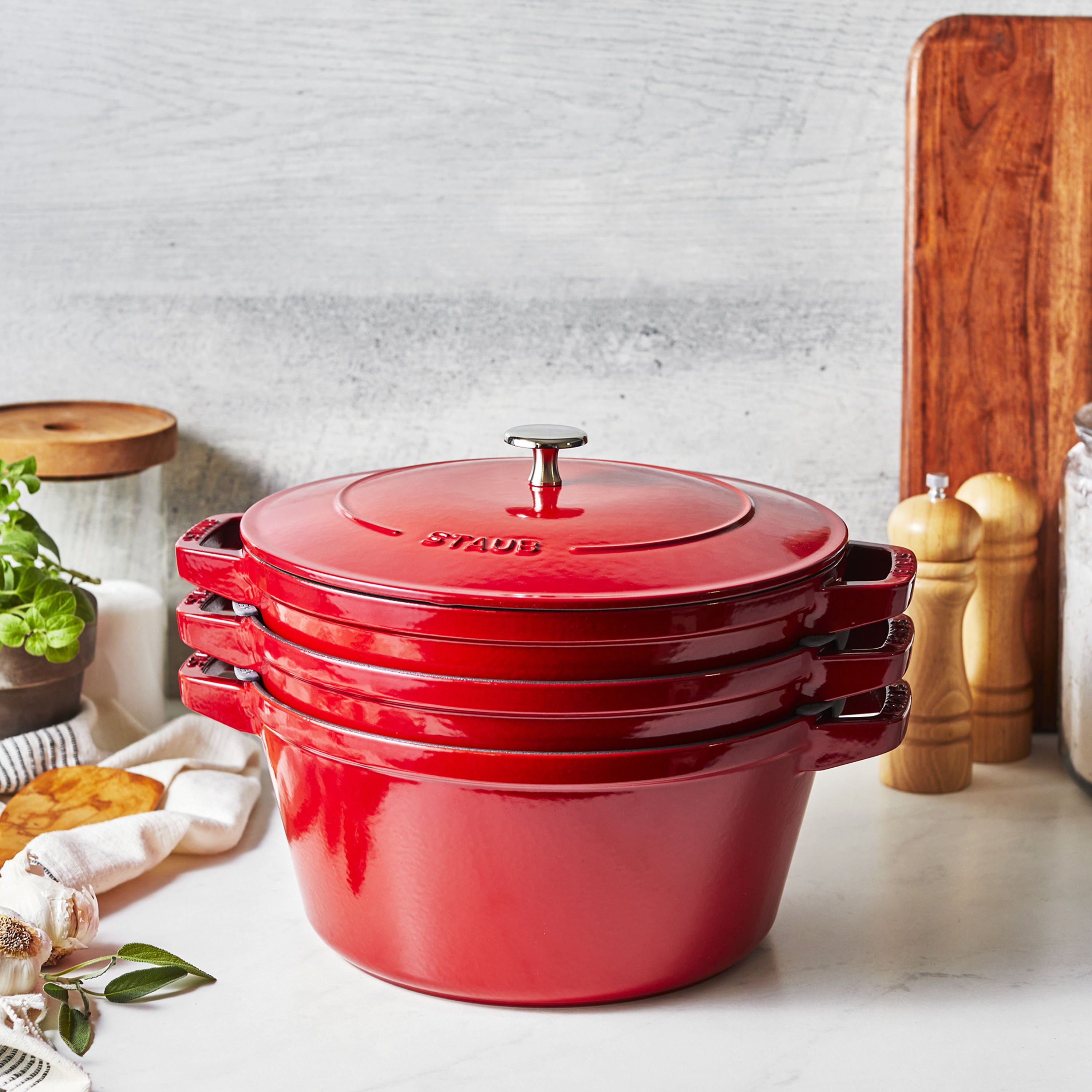 Red Staub cookware set on a kitchen counter with a neutral background