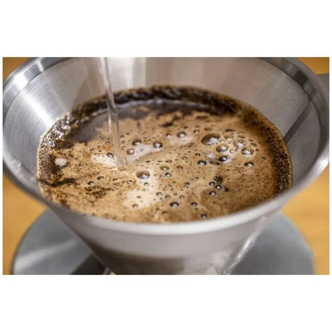 Coffee being poured into a metal filter basket.