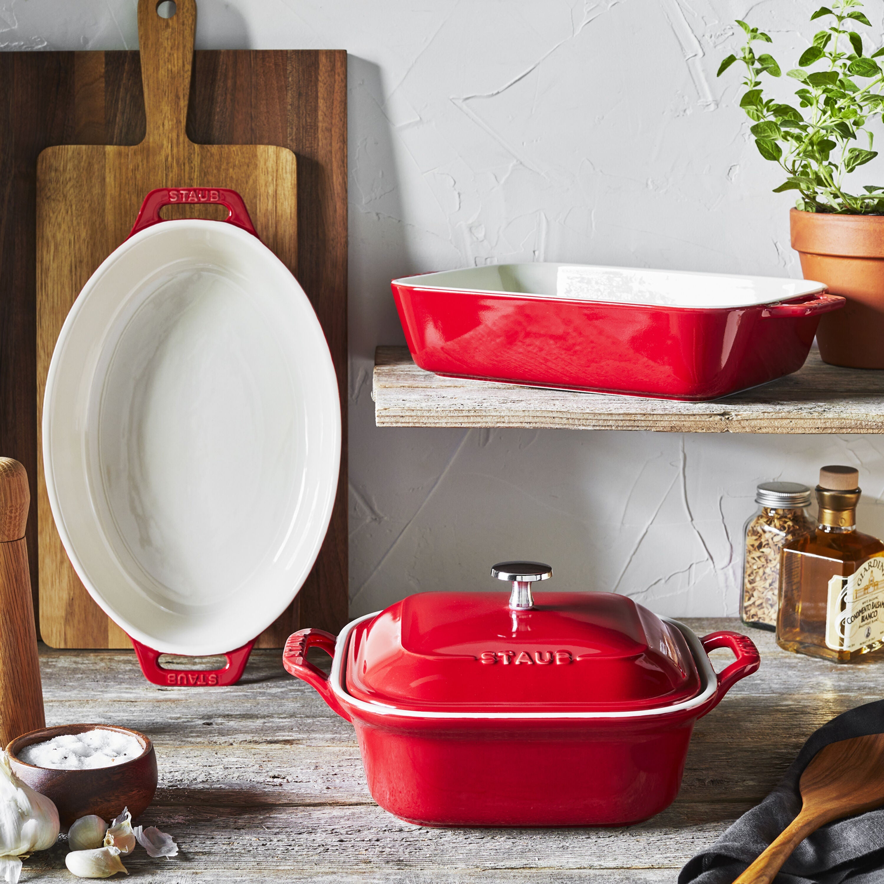 Red STAUB Ceramique Mixed Baking Dish Set on kitchen counter with wooden cutting board and herbs.