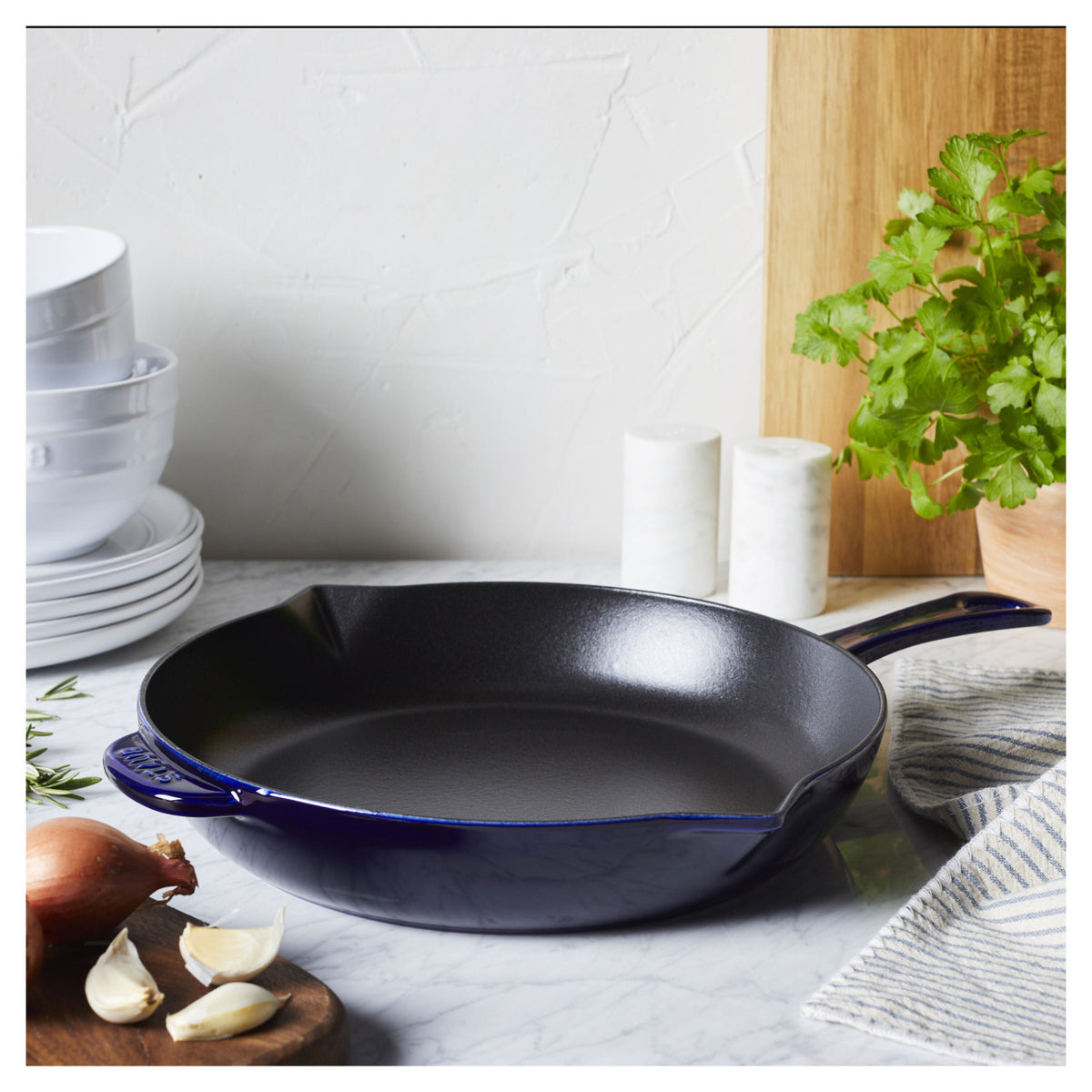 Blue frying pan on a kitchen counter with ingredients and decor