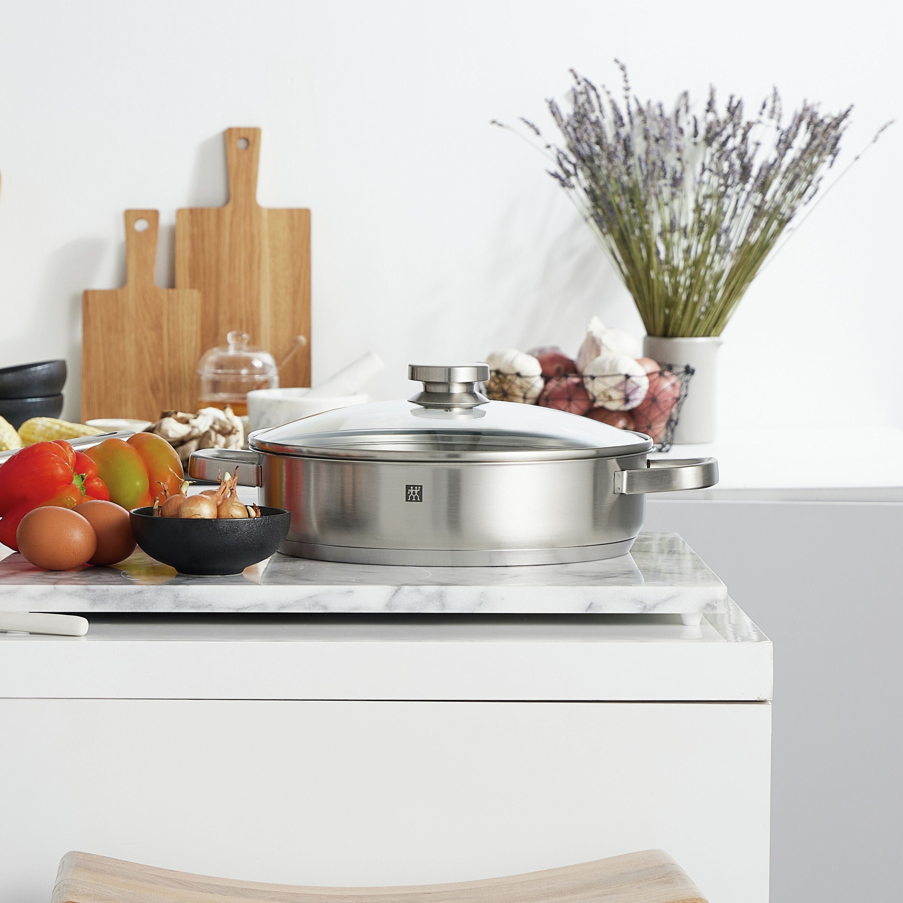Stainless steel Cooking with the Zwilling Joy 4.25 qt Saute Casserole on a kitchen counter with ingredients and decor.