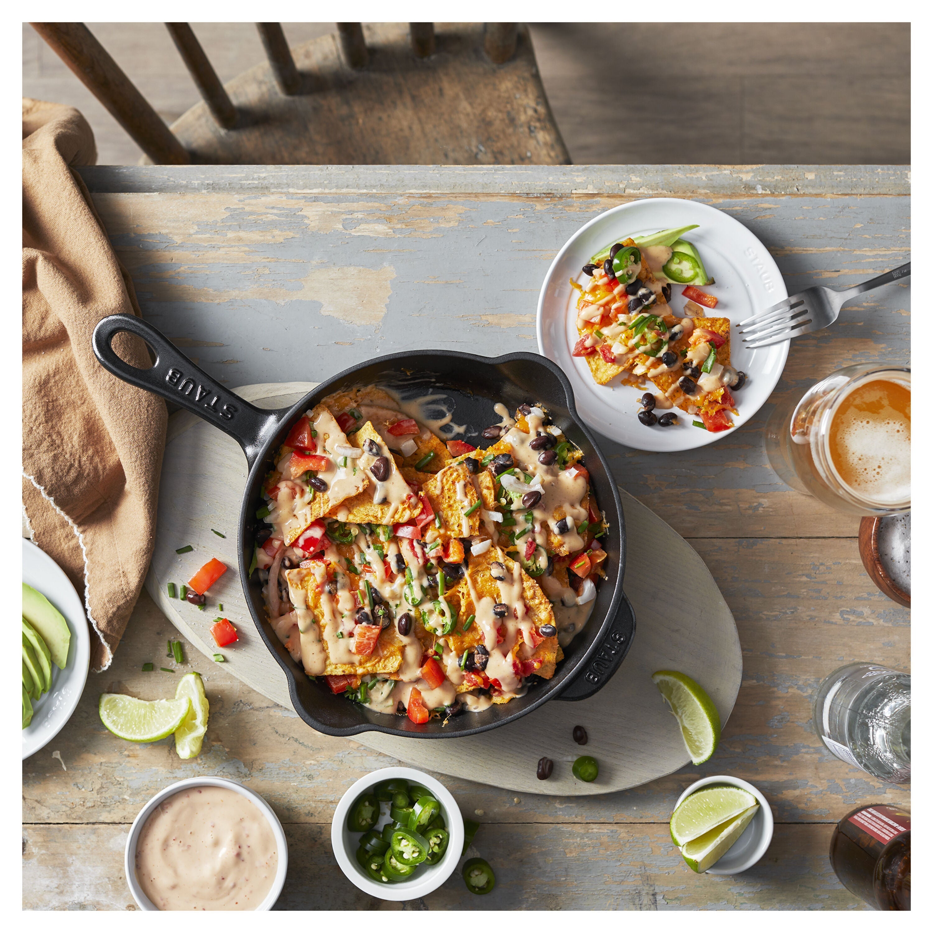 Nachos in a skillet with sides on a wooden table