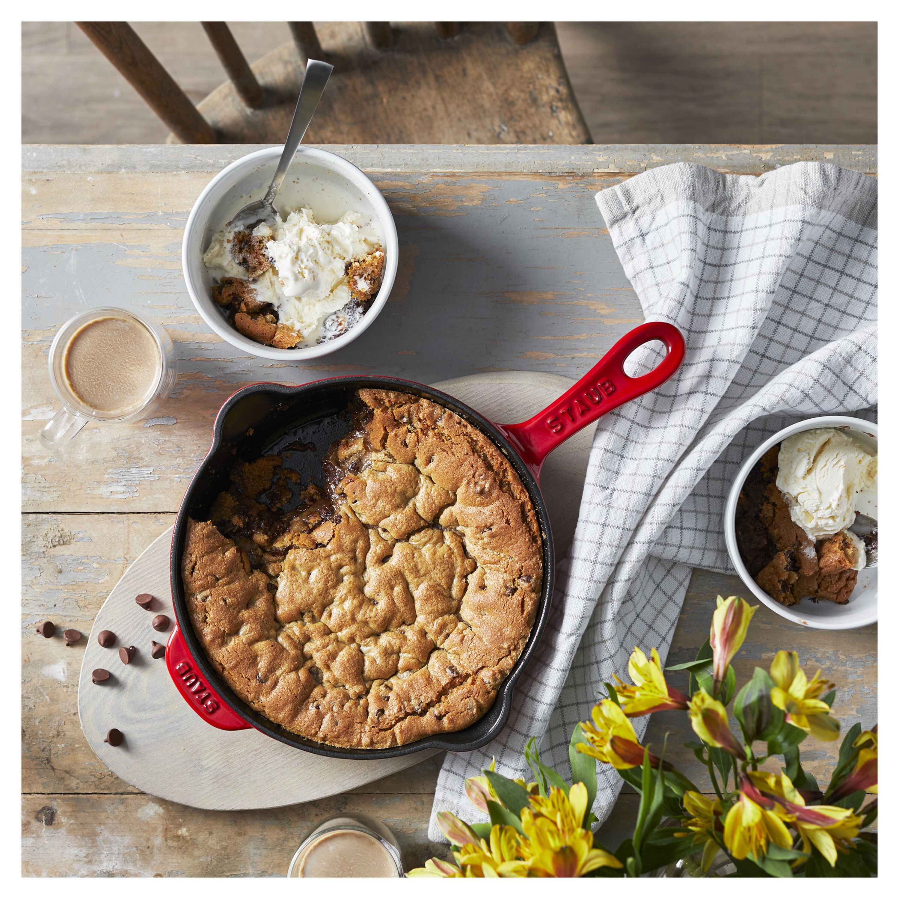 Skillet cookie on a wooden table with ice cream and coffee