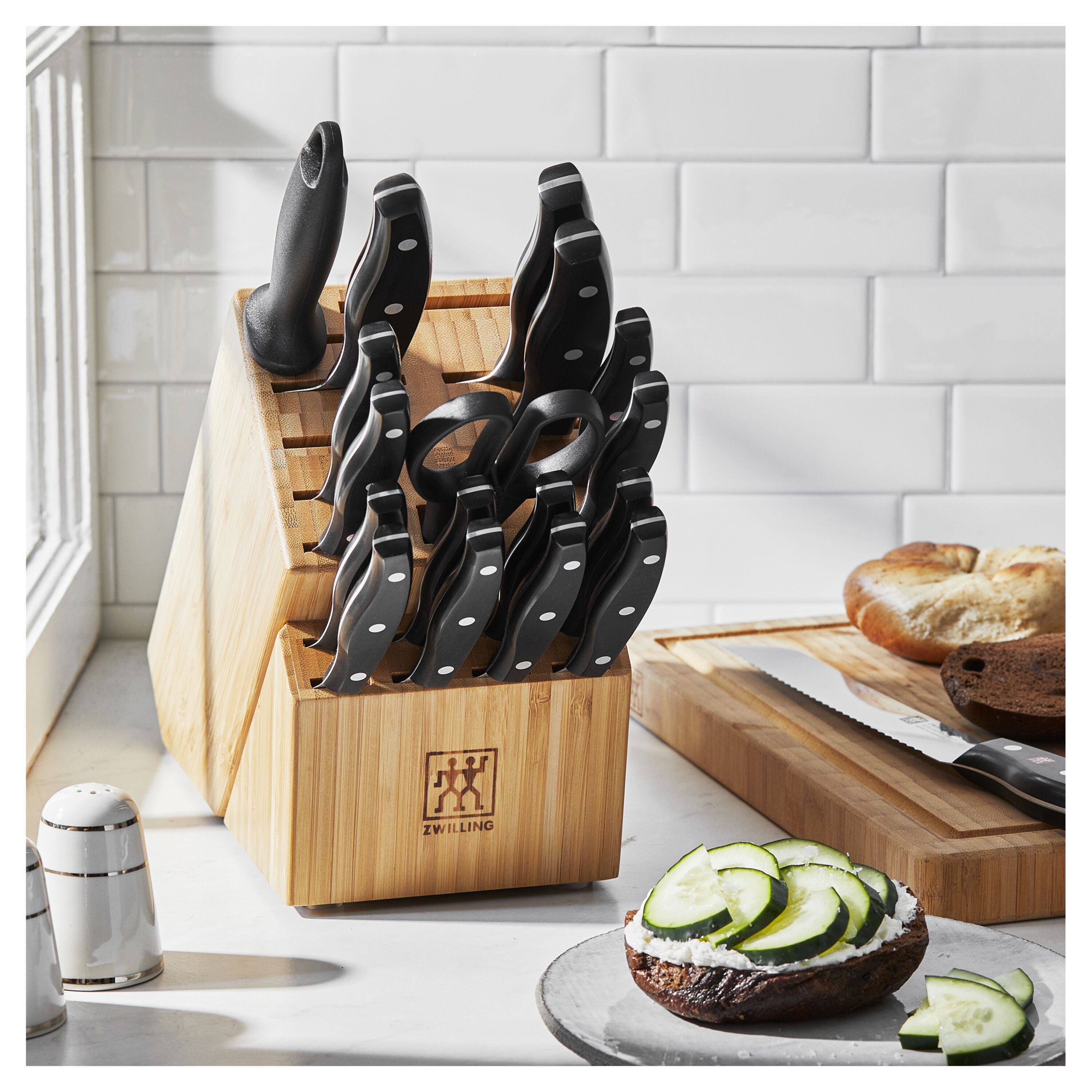 ZWILLING TWIN Signature 19-Pc German Steel Knife Set displayed on kitchen counter with bread and cucumber slices nearby.