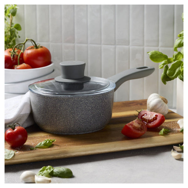 Gray speckled cookware set on a wooden cutting board with tomatoes and garlic
