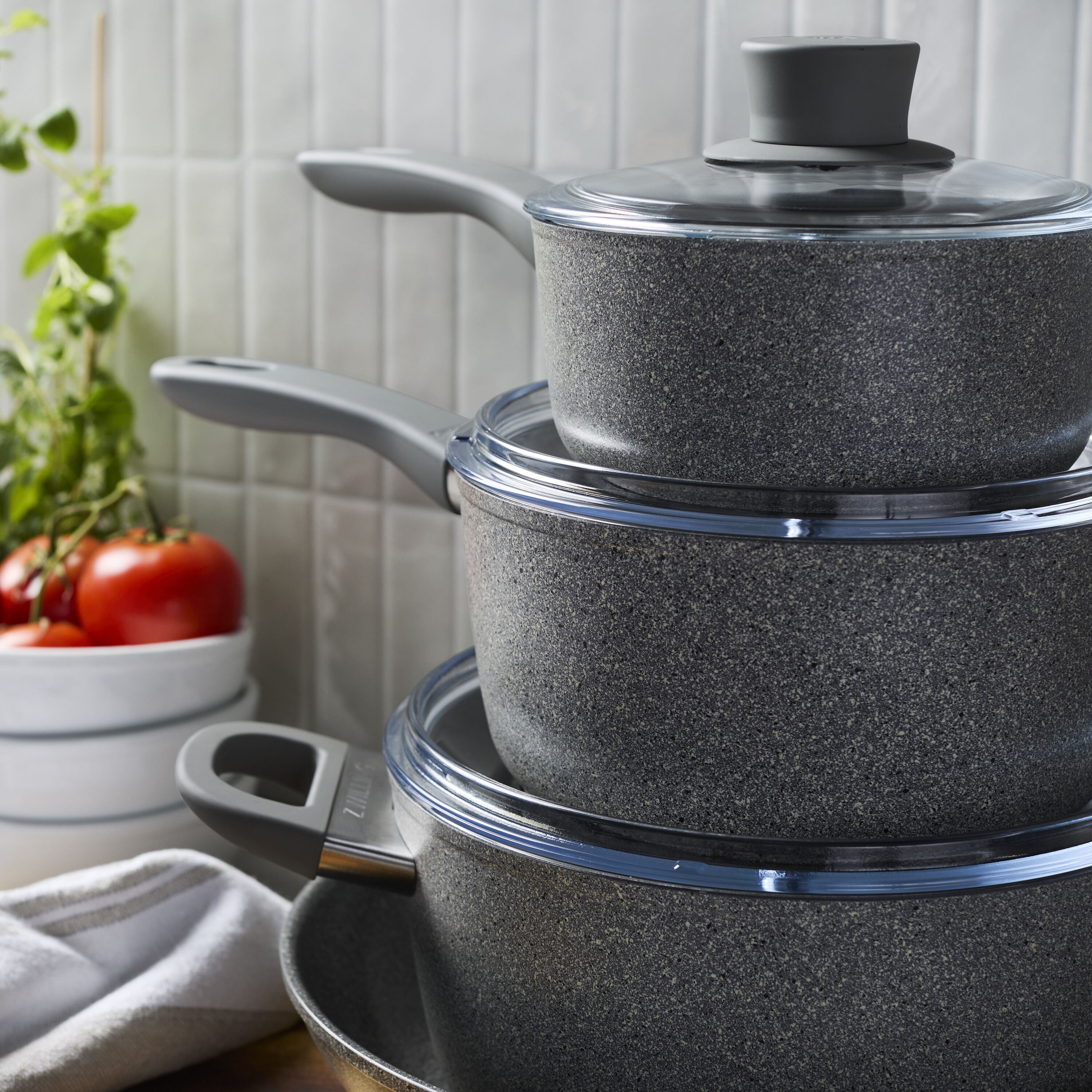 Set of black cookware with lids on a kitchen counter