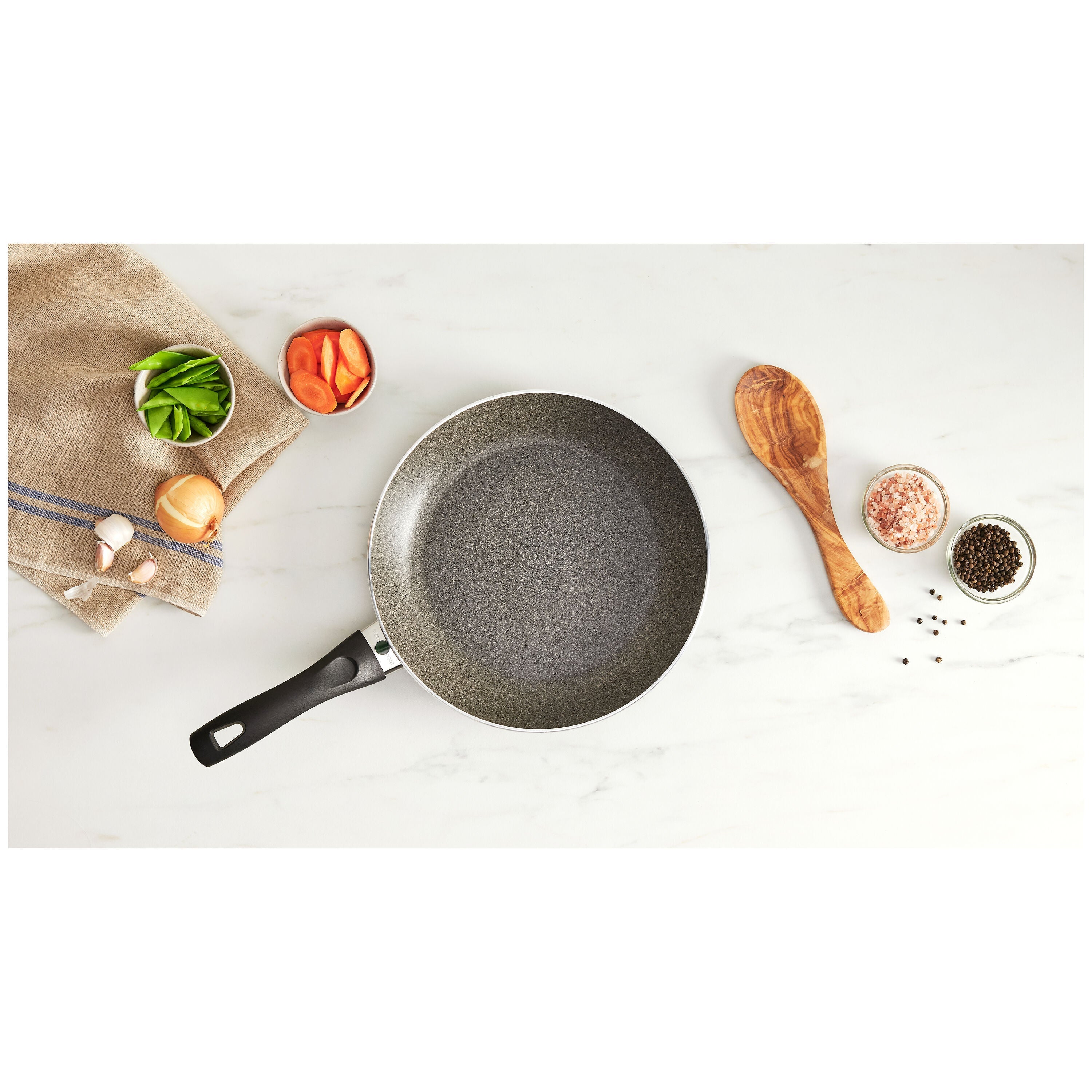 Frying pan on a white surface with kitchen items around