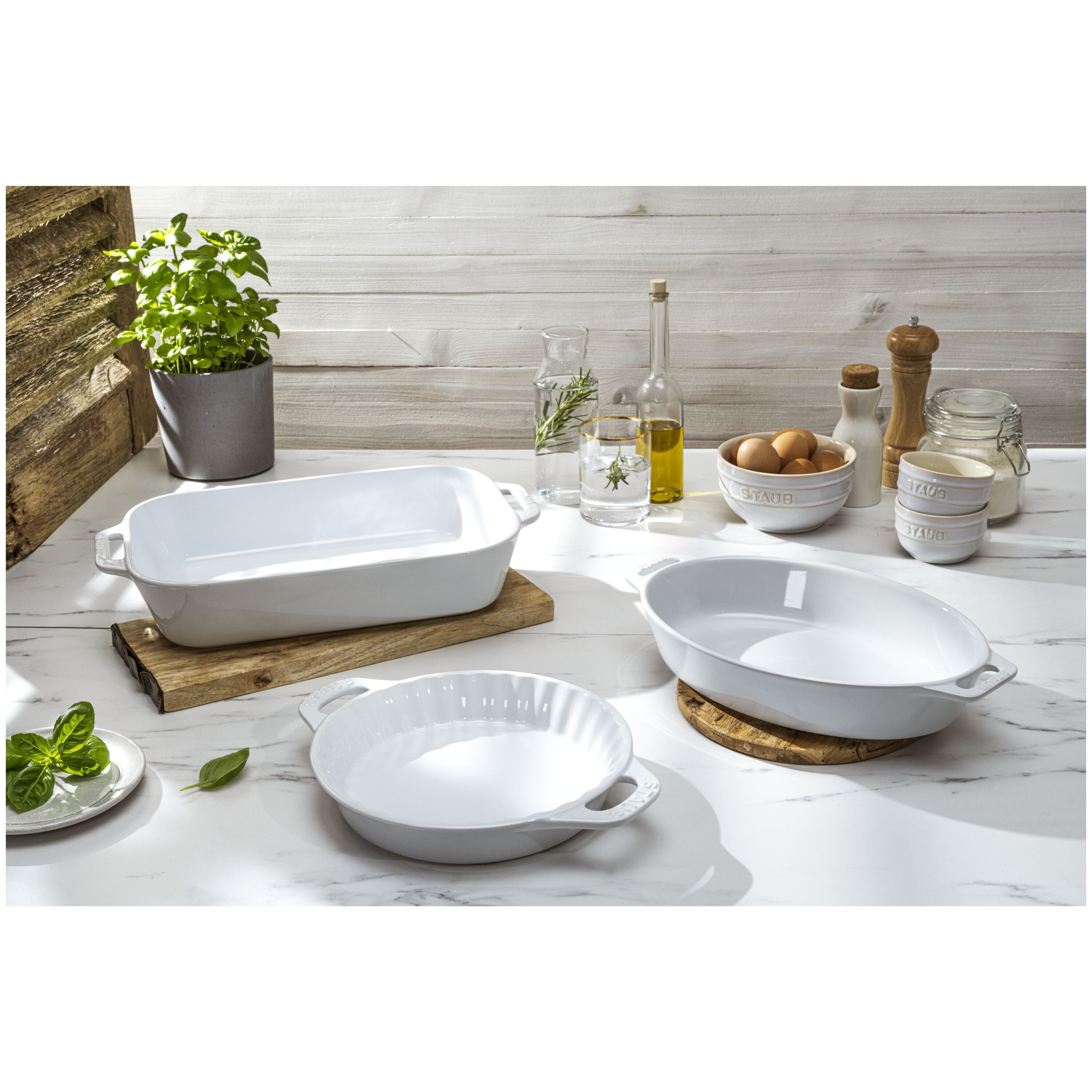 STAUB Ceramique Mixed Baking Dish Set White 3 Piece on kitchen counter with herbs and baking ingredients.
