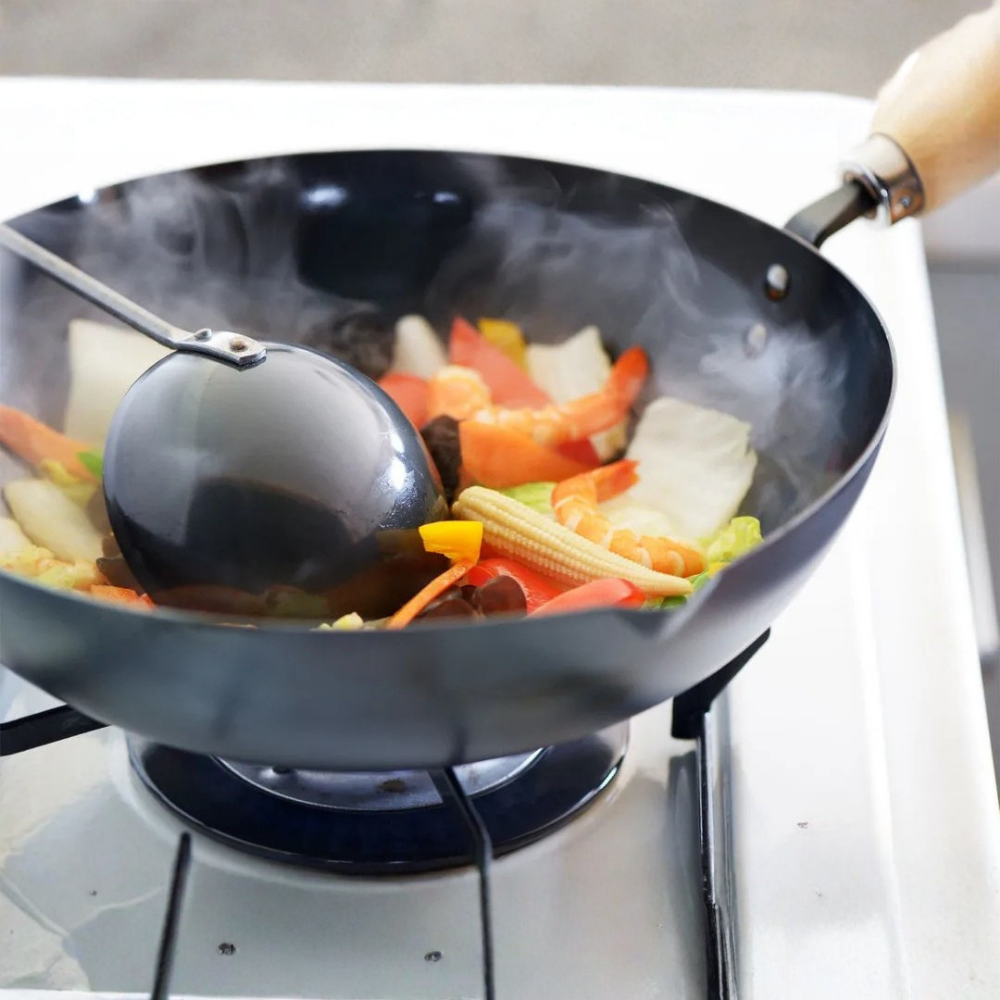 Wok with vegetables being cooked on a stove