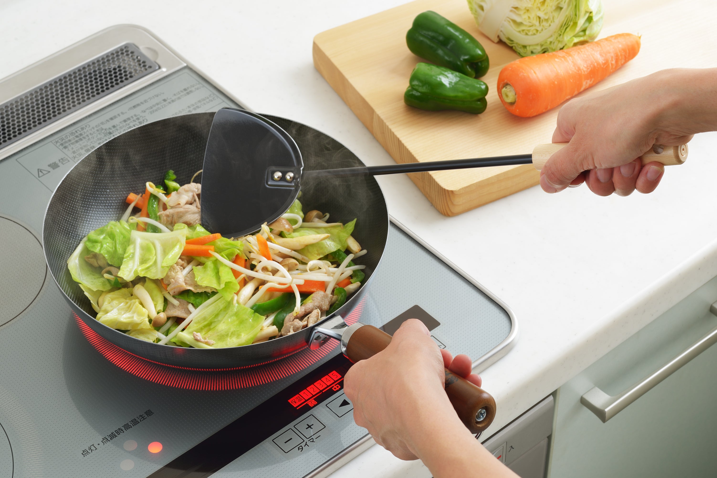 Yoshikawa Cook-Pal Chinese Metal Spatula in use for stir-frying vegetables on a stove, showcasing its ergonomic design and heat-resistant handle.