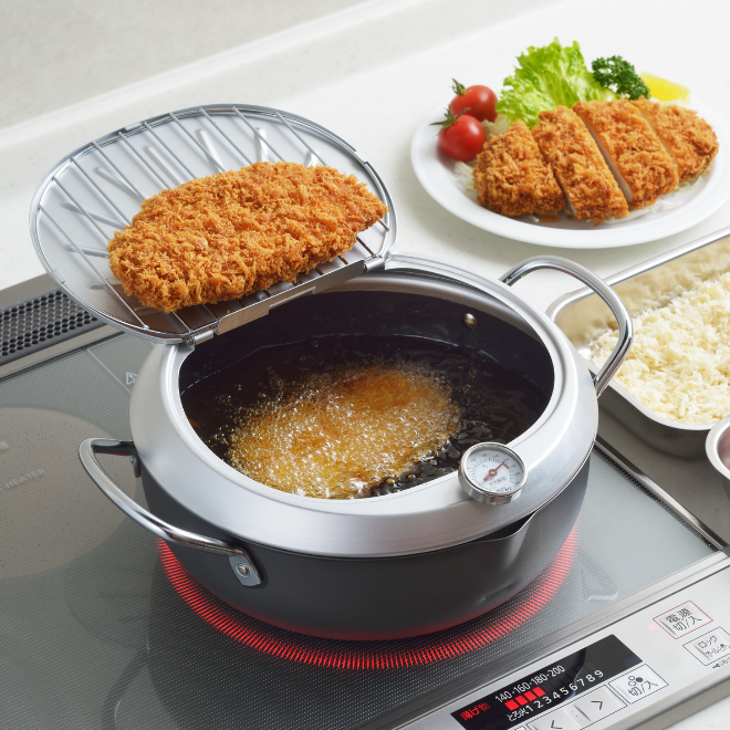 YOSHIKAWA GOGI Tempura Pot 24 cm with food on a stove, surrounded by ingredients and a plate of prepared dishes.