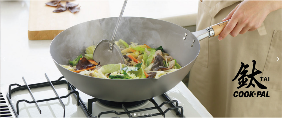 Chef using the Yoshikawa Cook-Pal TAI titanium wok on a gas stove for stir-fry