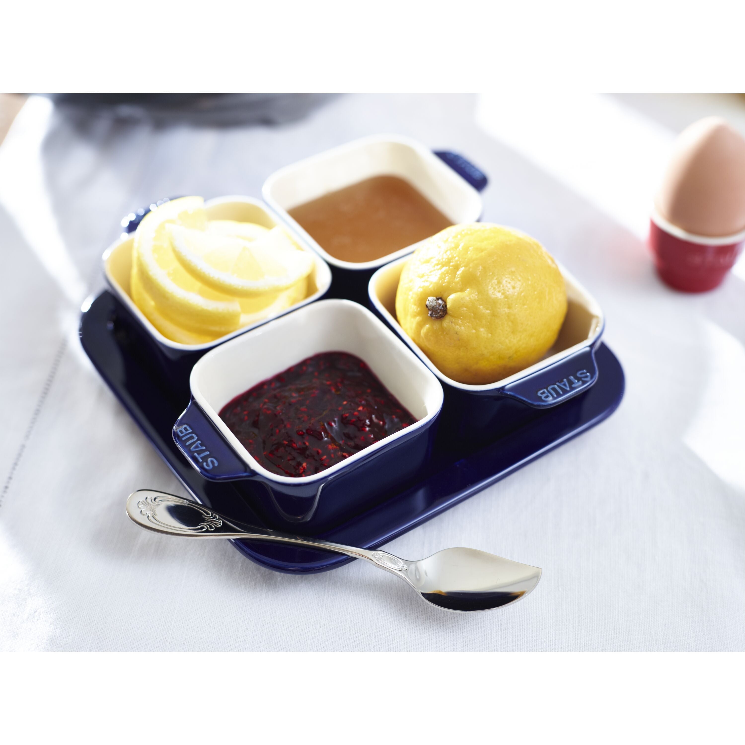 Set of four small dishes with different food items on a blue tray with a spoon.