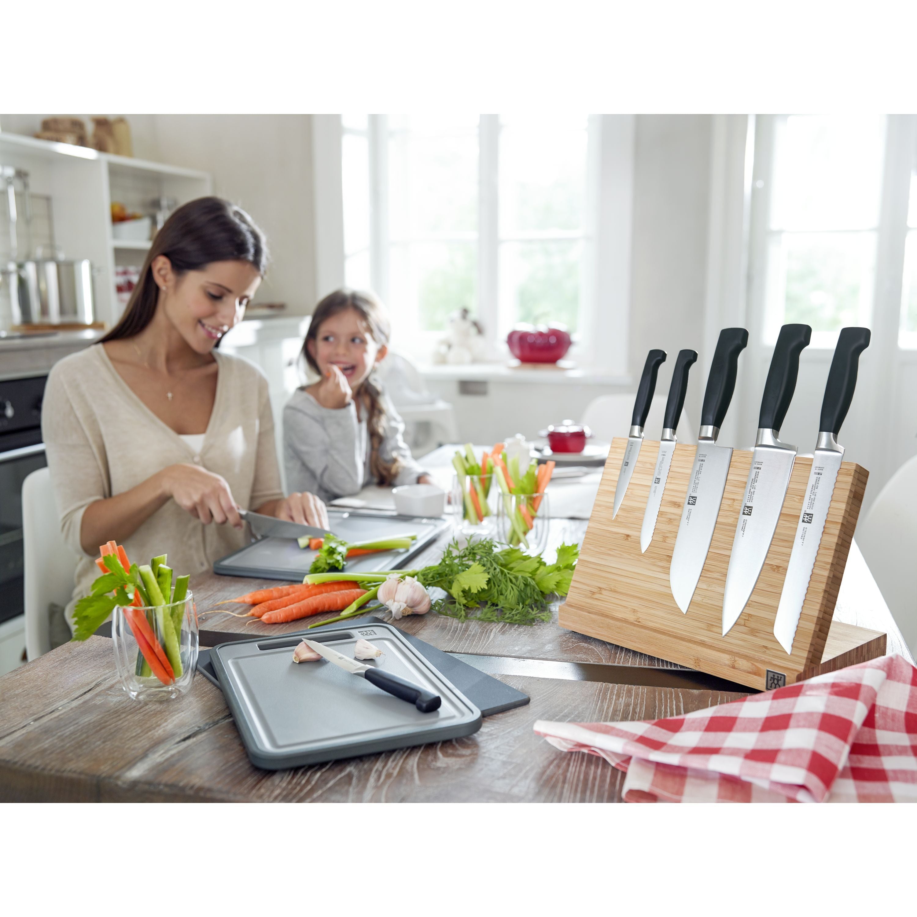 Woman and child preparing food in a kitchen with knives and cutting boards.