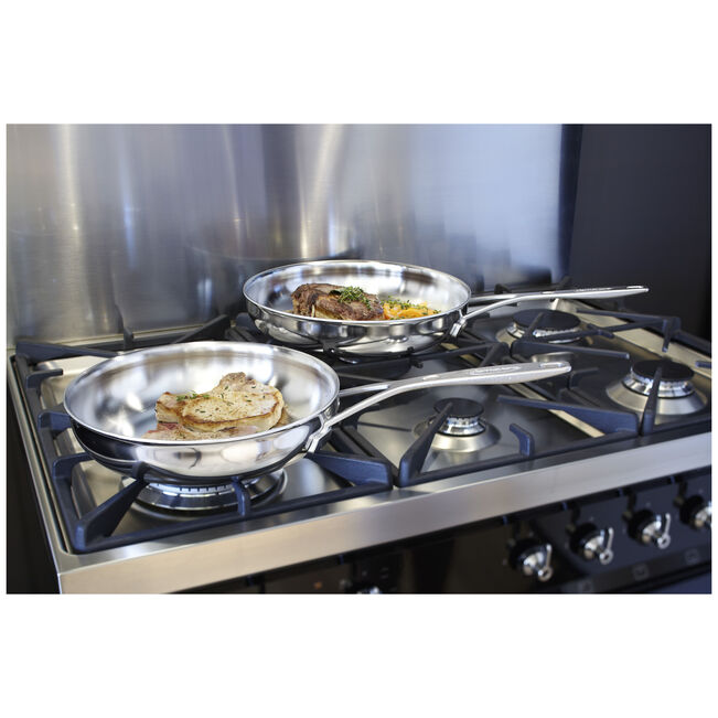 Stainless steel cookware on a gas stove with food being cooked.