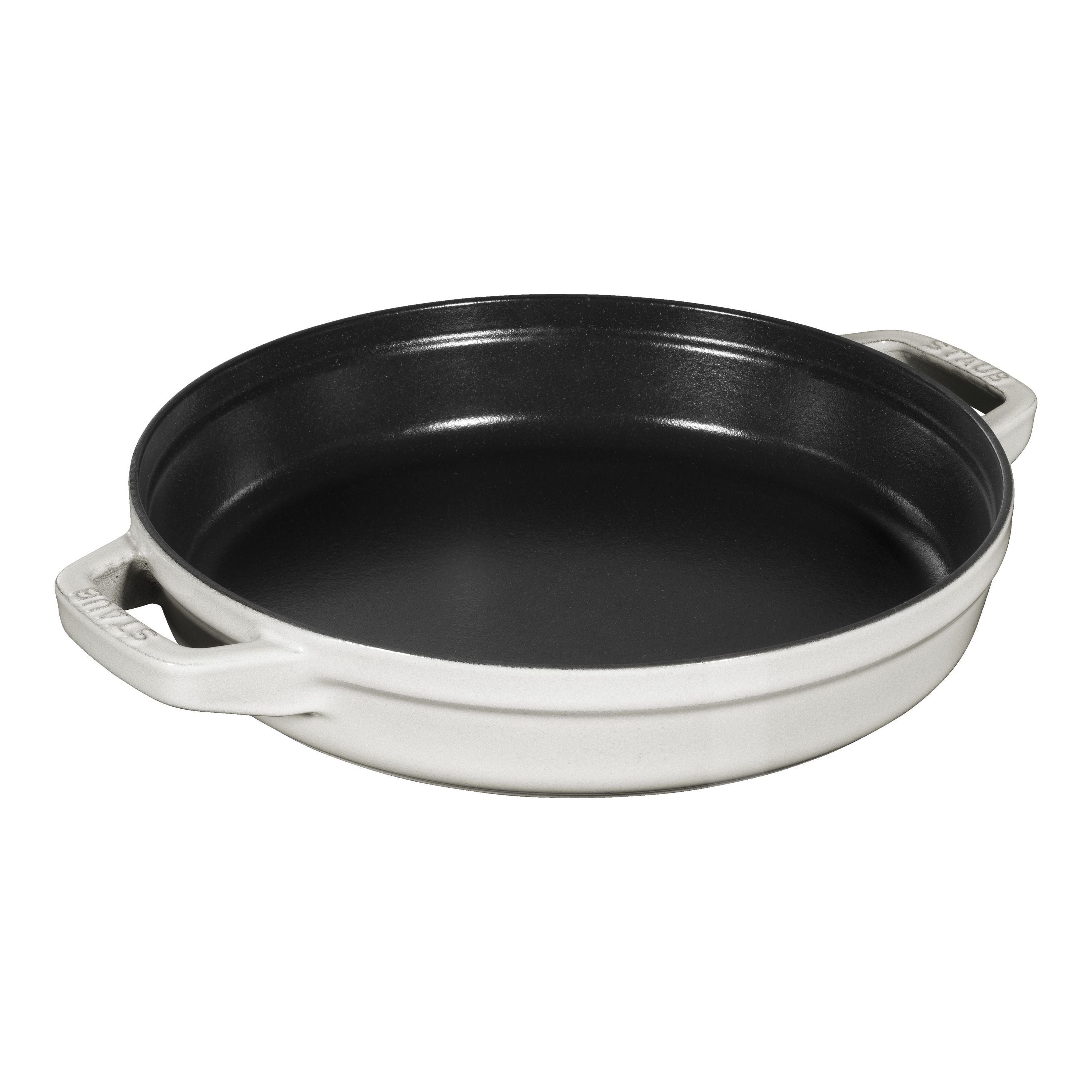 Black cast iron skillet with white handles on a white background